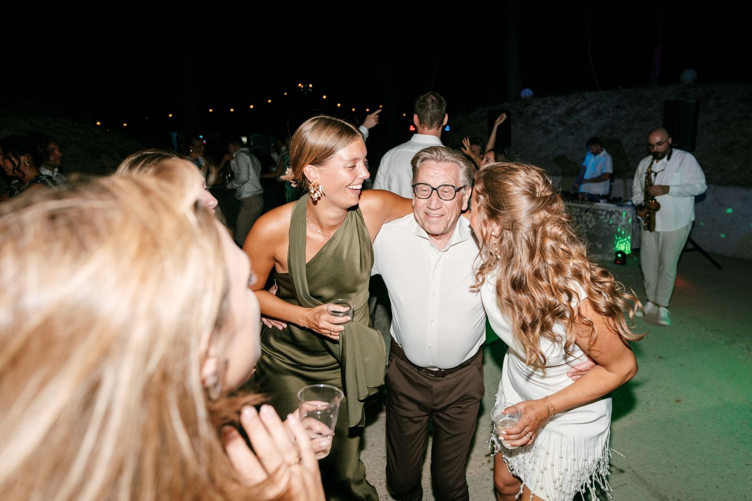 Guests laughing and dancing together at an outdoor evening wedding reception party.