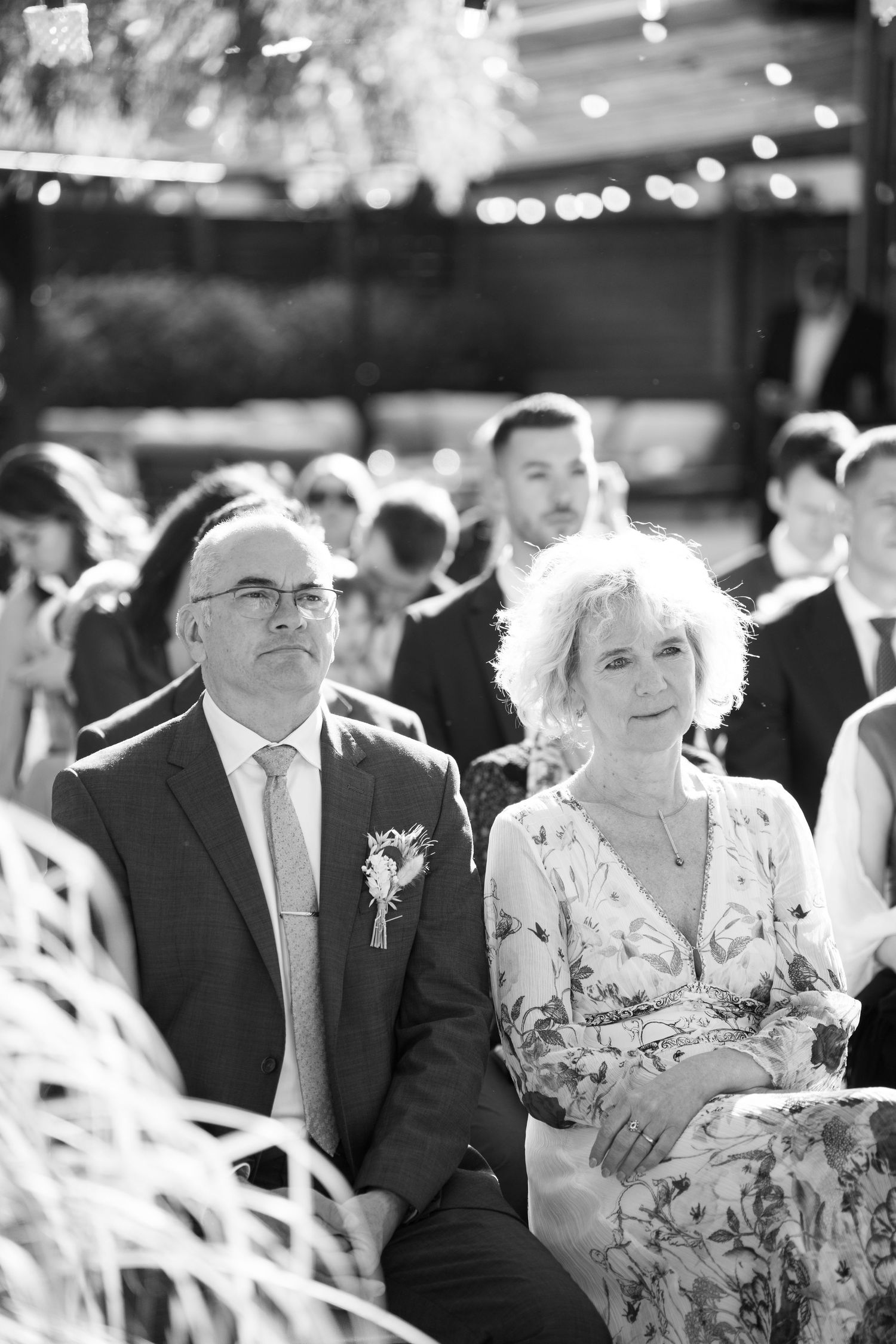 Black and white photo of wedding guests seated during outdoor ceremony watching proceedings. Mallorca wedding photographer and filmmaker.
