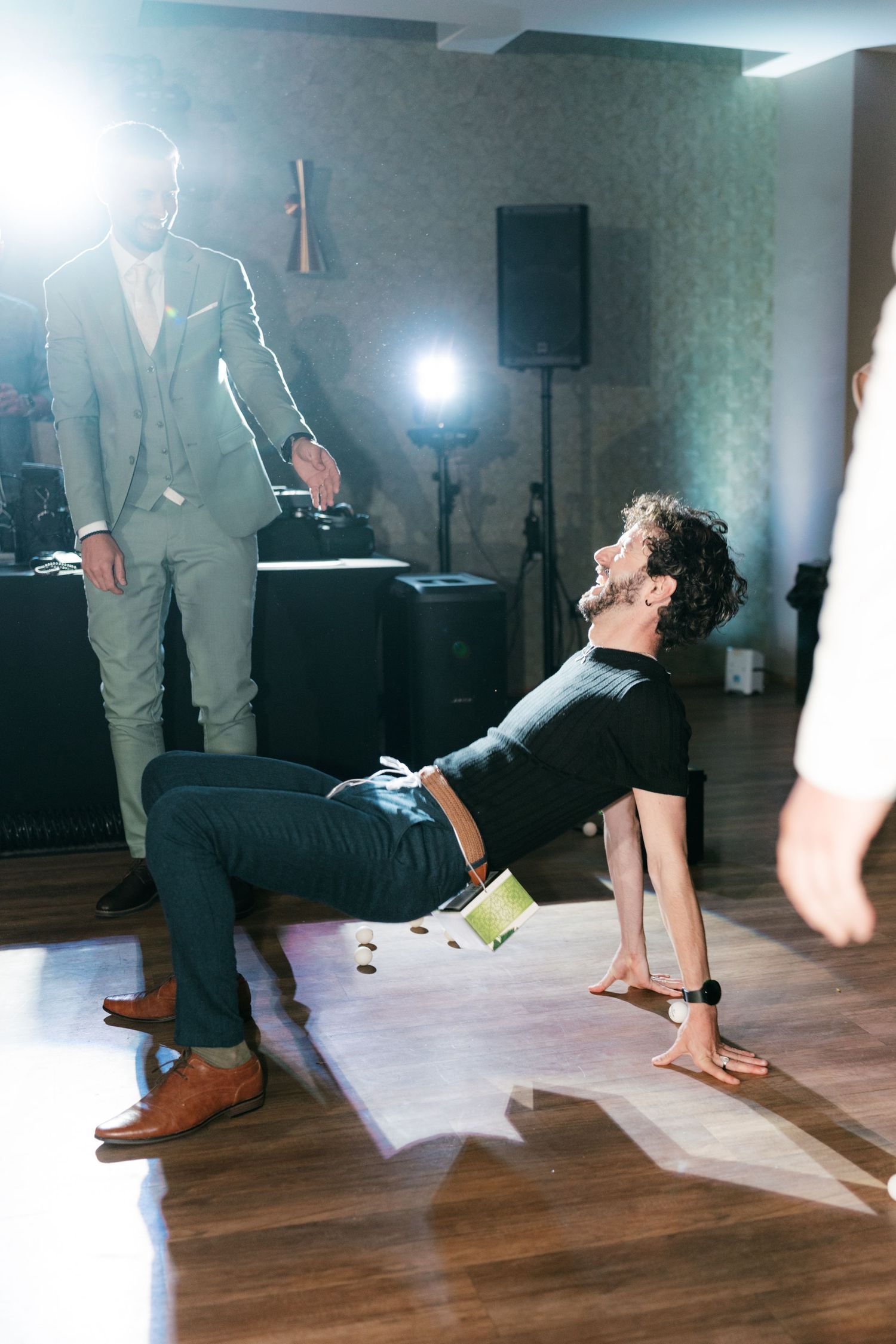 Man doing limbo dance at wedding reception under bright stage lights. Italy wedding photographer and filmmaker