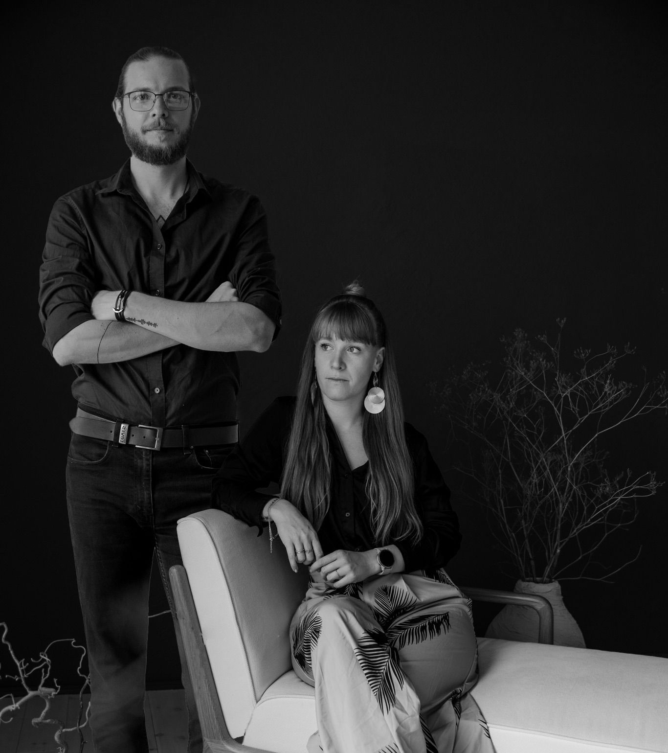 Black and white portrait of a man and woman posing together in a modern studio setting.
