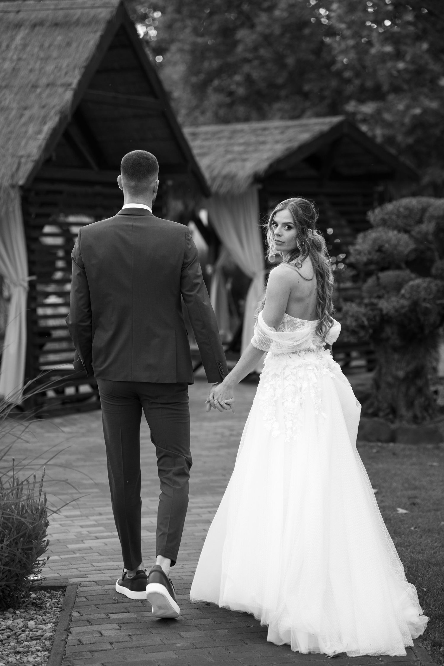 Black and white photo of bride and groom walking hand in hand at wedding venue. Mallorca wedding photographer and filmmaker.
