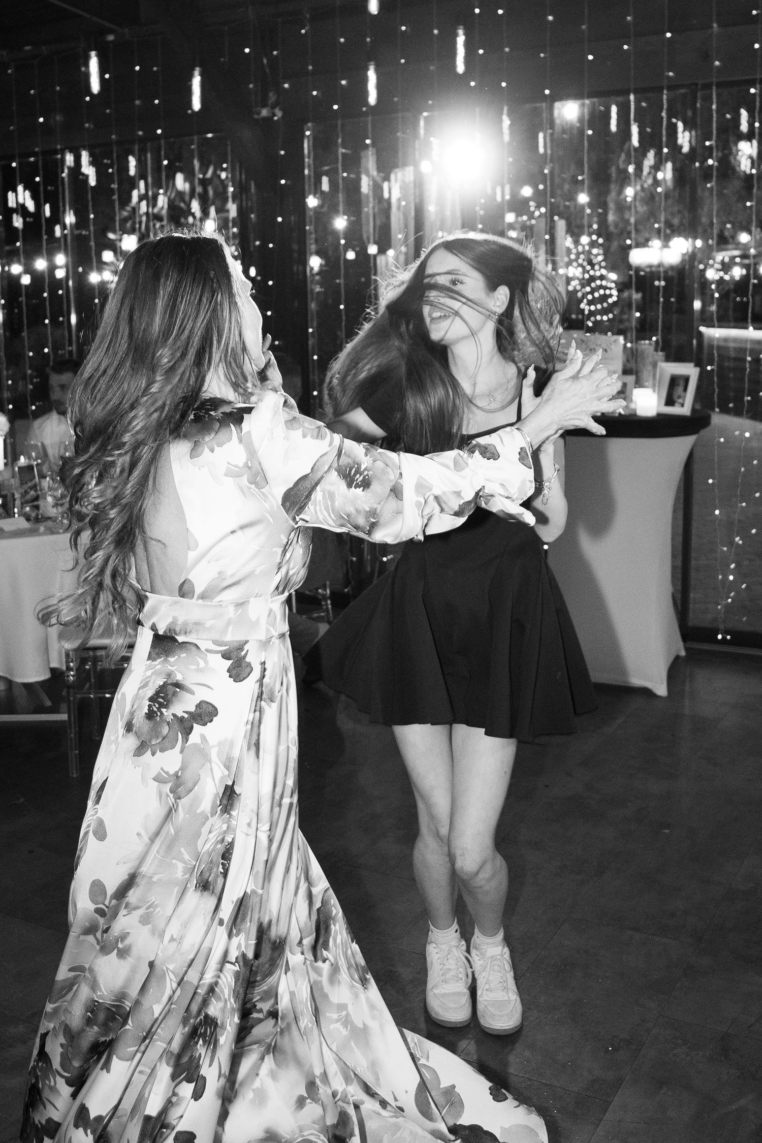 Black and white photo of two women laughing and dancing together at a wedding reception celebration. Mallorca wedding photographer and film