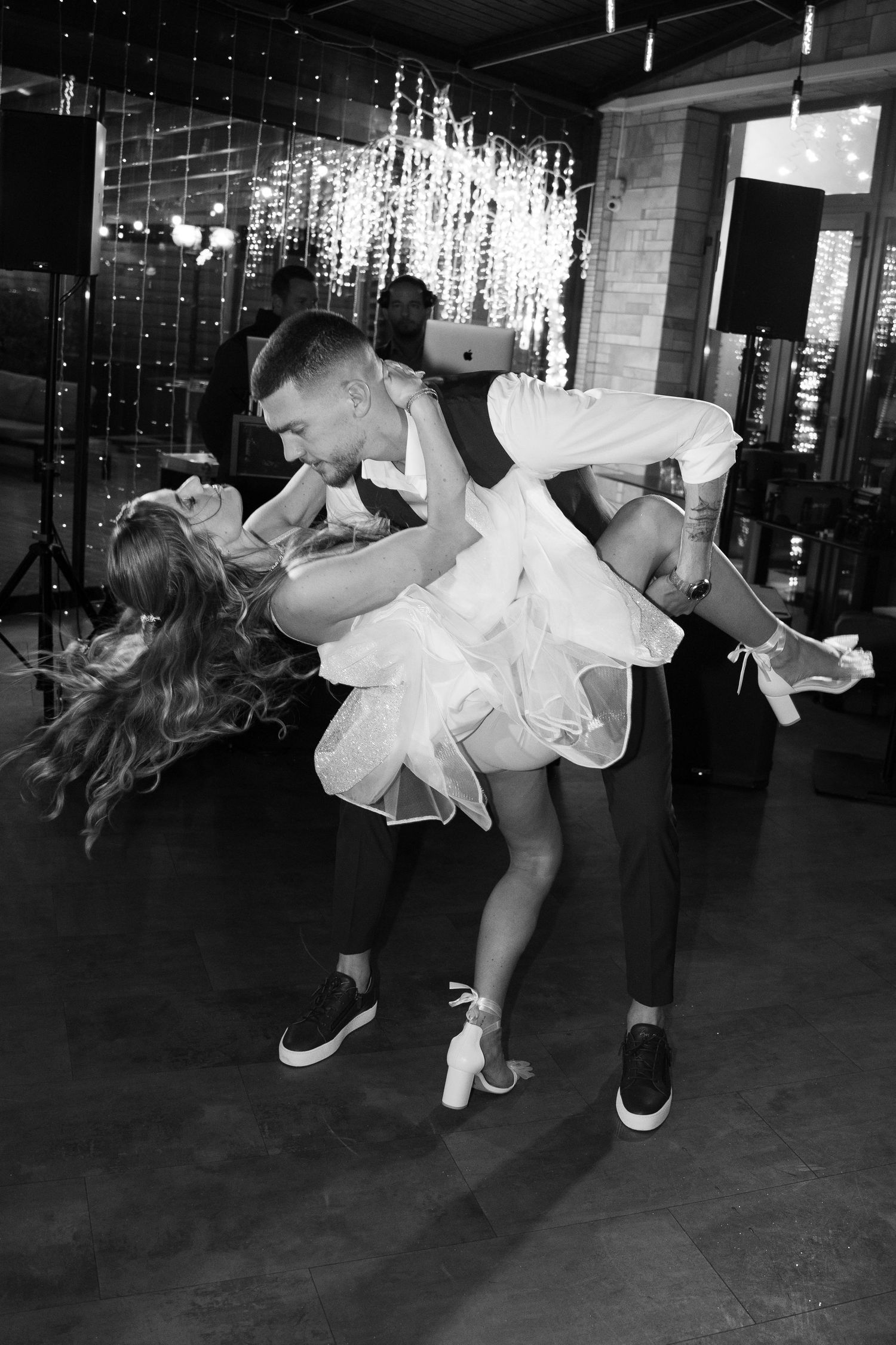 Black and white photo of groom lifting and dipping bride in sparkly short dress on the dance floor. Mallorca wedding photographer and film