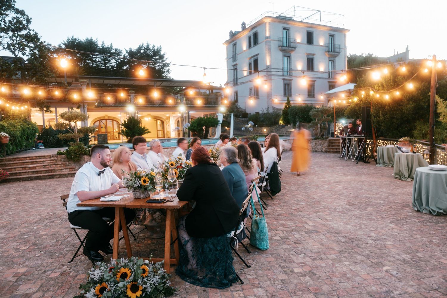 Romantic outdoor wedding reception dinner under string lights at a rustic Italian villa at dusk. Tuscany wedding photographer, filmmaker