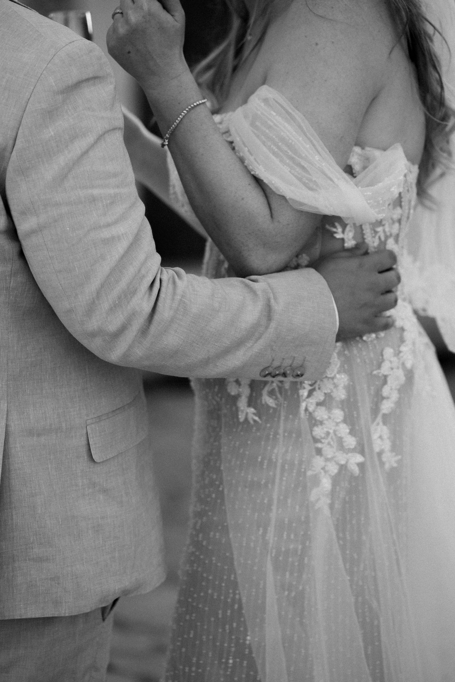 Black and white photo of a bride in a floral lace gown and groom in a suit embracing during their wedding. Mallorca wedding photographer.