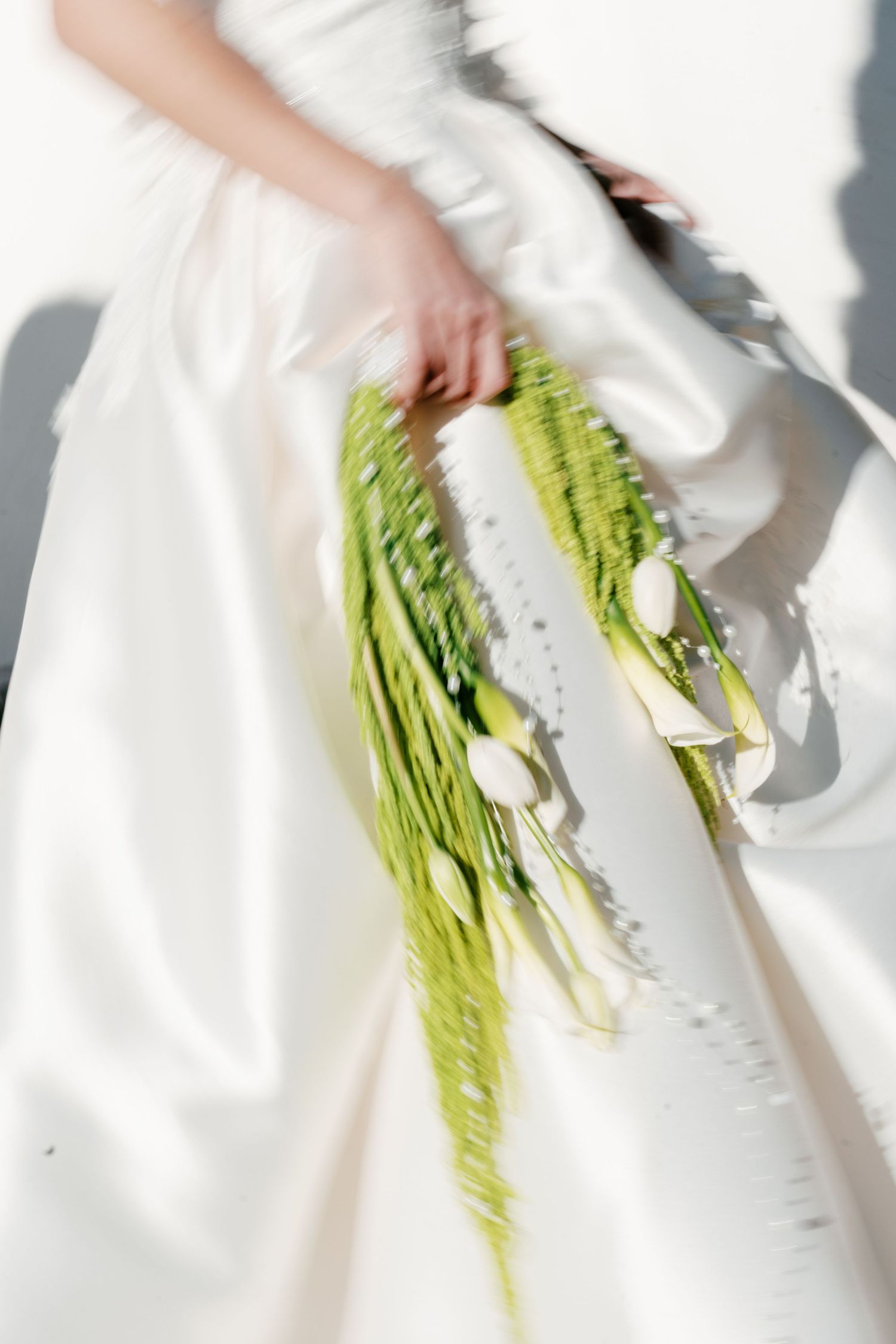 Bride in white wedding dress holding a cascading bouquet of white tulips and green foliage. Mallorca wedding photographer, filmmaker