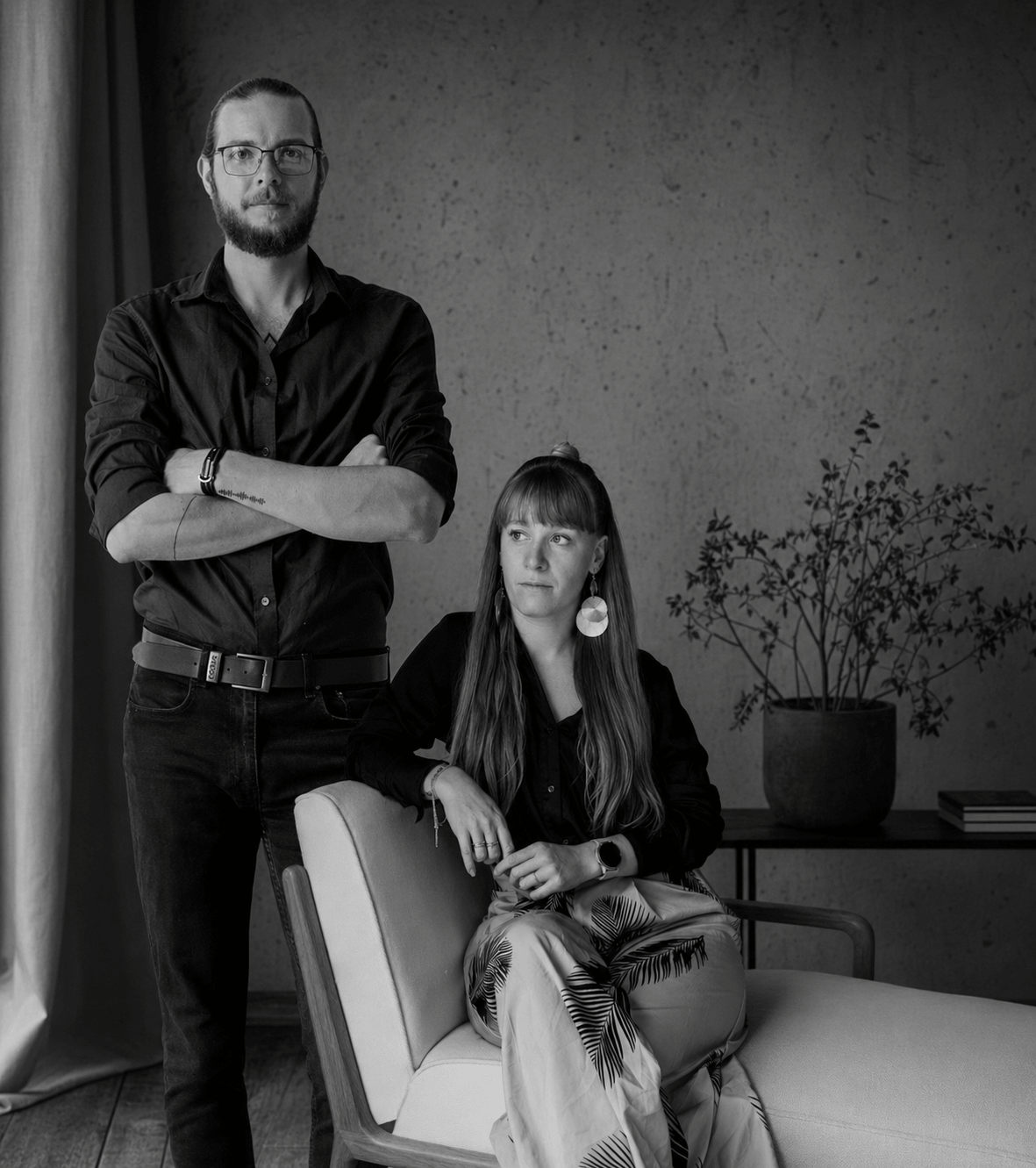 Black and white portrait of a man and woman in elegant dark attire, posing in a modern interior setting in Tuscany.