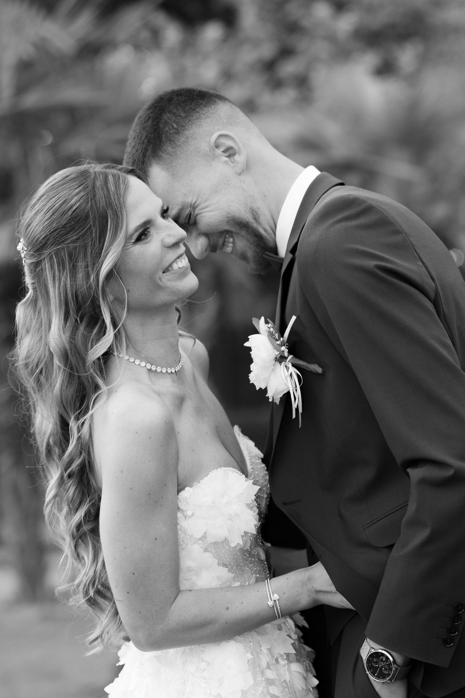 Black and white portrait of laughing bride and groom touching foreheads in romantic embrace. Mallorca wedding photographer and filmmaker.
