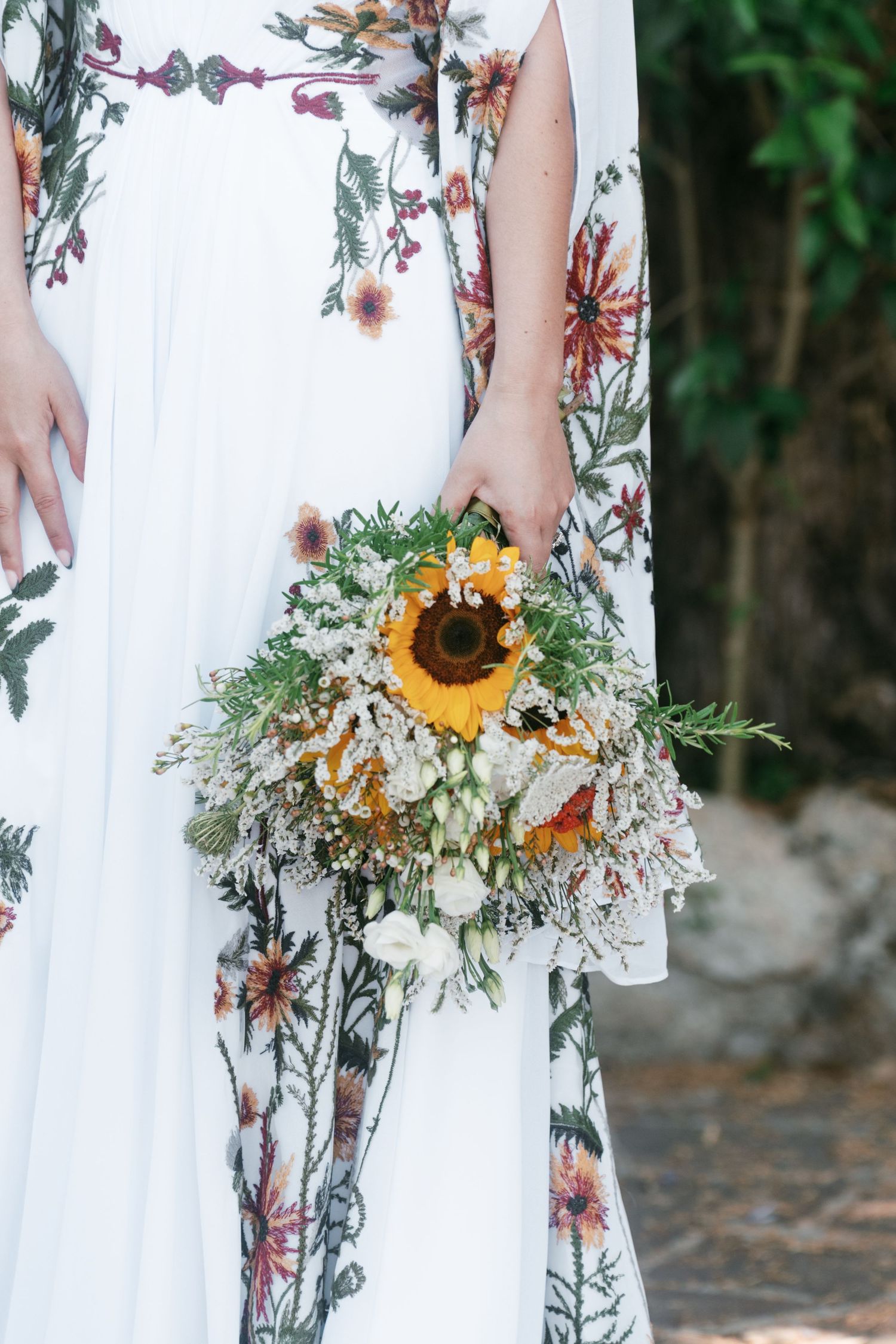 Bride holding a wildflower bouquet with sunflowers against her floral embroidered white wedding gown. Tuscany wedding photographer, filmmake