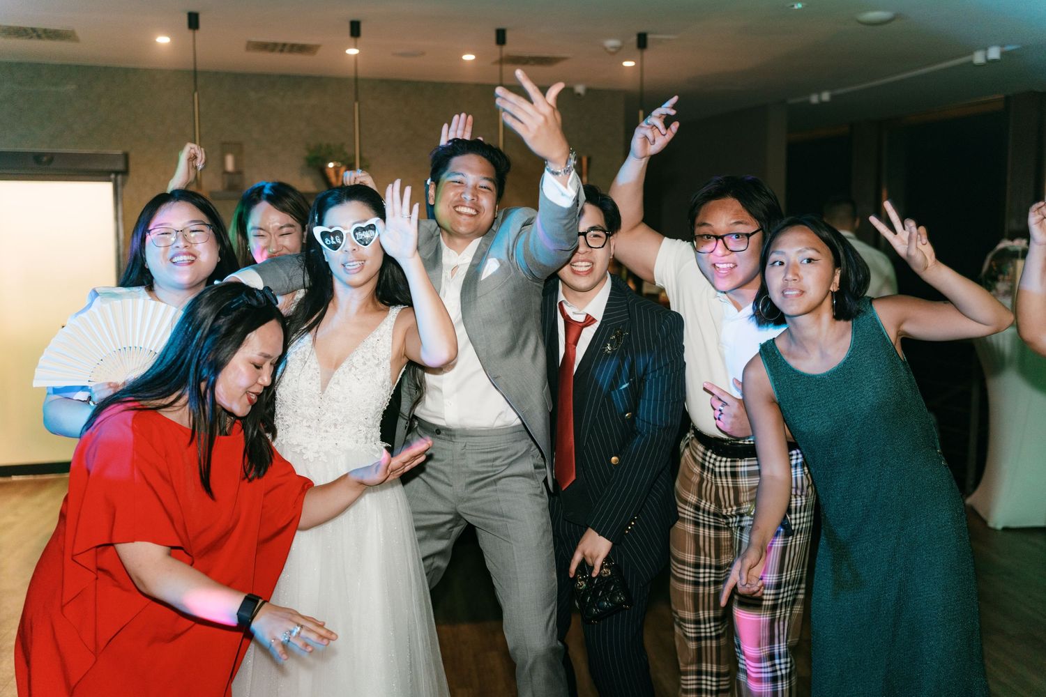 Wedding party group photo with bride and groom celebrating joyfully with friends raising hands. Italy wedding photographer