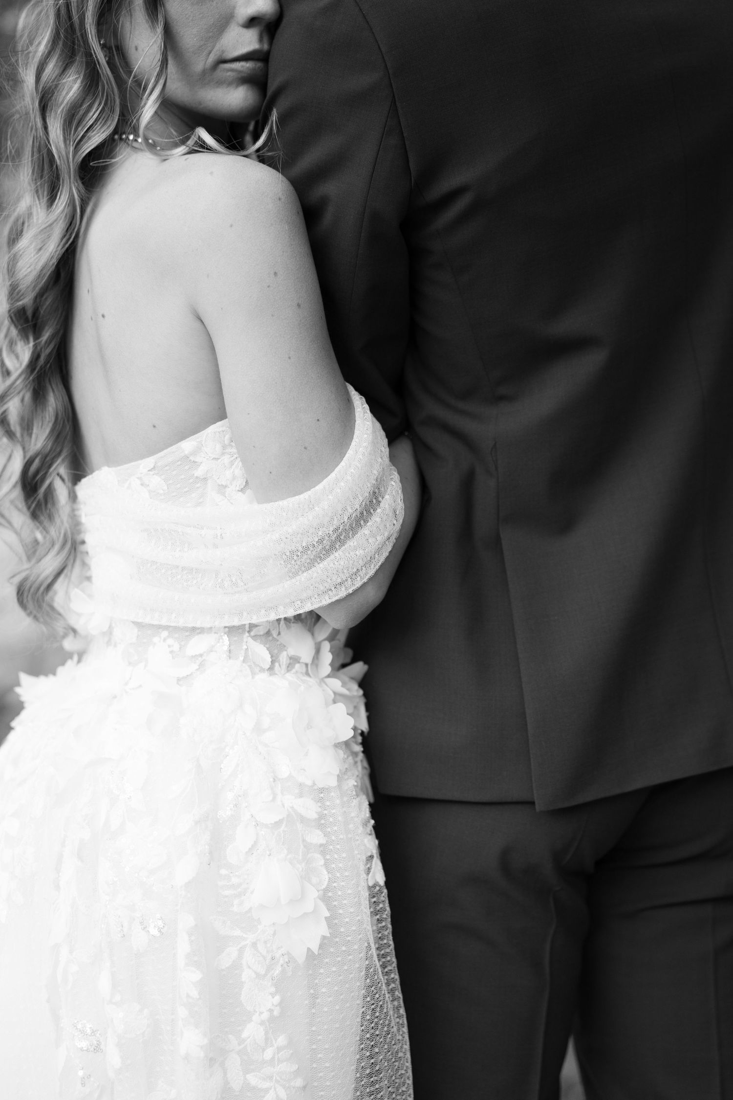 Black and white close-up of bride in strapless lace wedding gown standing beside groom in dark suit. Mallorca wedding photographer and filmm