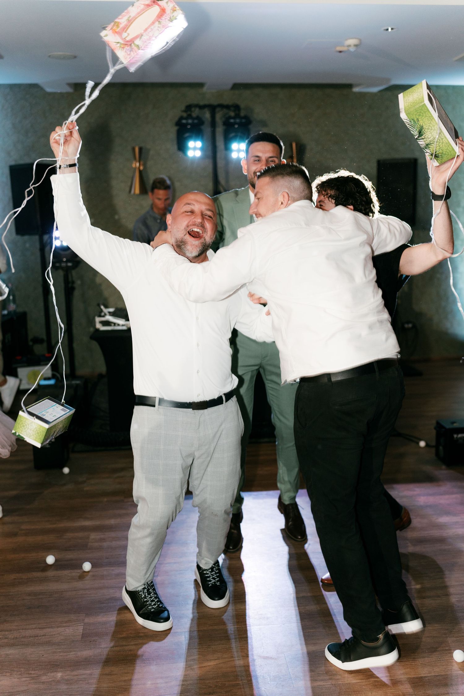 Excited men jumping and celebrating with boxes at wedding reception. Italy wedding photographer and filmmaker