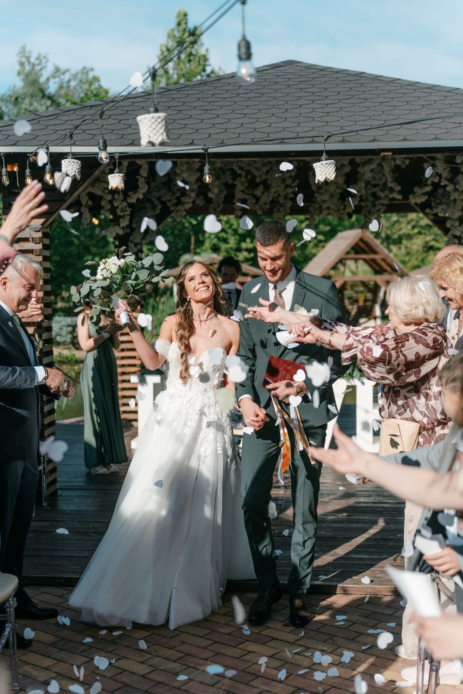 Smiling bride and groom walk through confetti shower surrounded by cheering wedding guests. Mallorca wedding photographer and filmmaker.