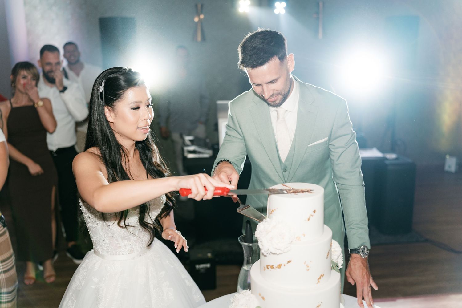 Bride and groom cutting their white wedding cake together at their wedding reception. Italy wedding photographer and filmmaker