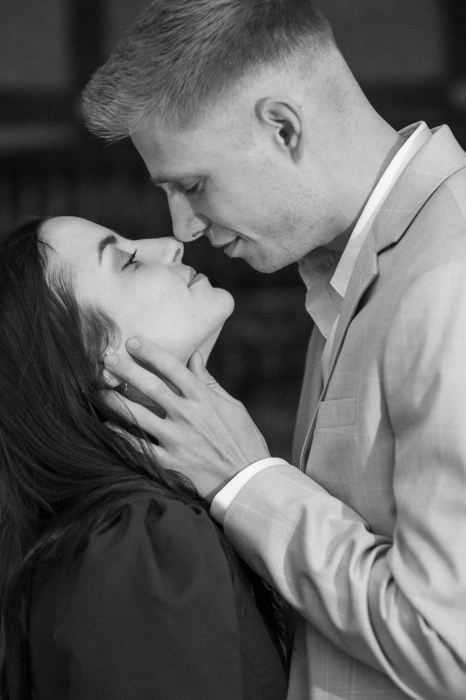 Black and white photo of a romantic couple almost kissing, man tenderly holding womans face.