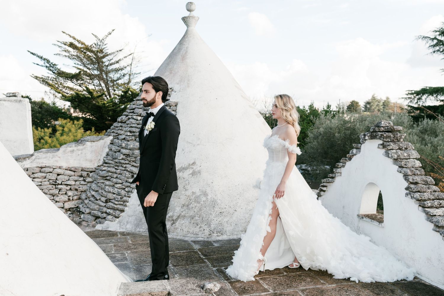 Bride and groom stand atop trulli rooftops in Alberobello, Italy on their wedding day. Puglia wedding photographer, film