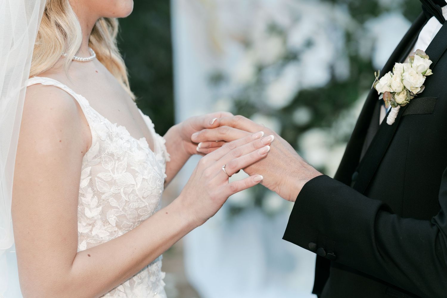 Close-up of groom placing wedding ring on brides finger during elegant outdoor wedding ceremony. Puglia wedding photographer, film