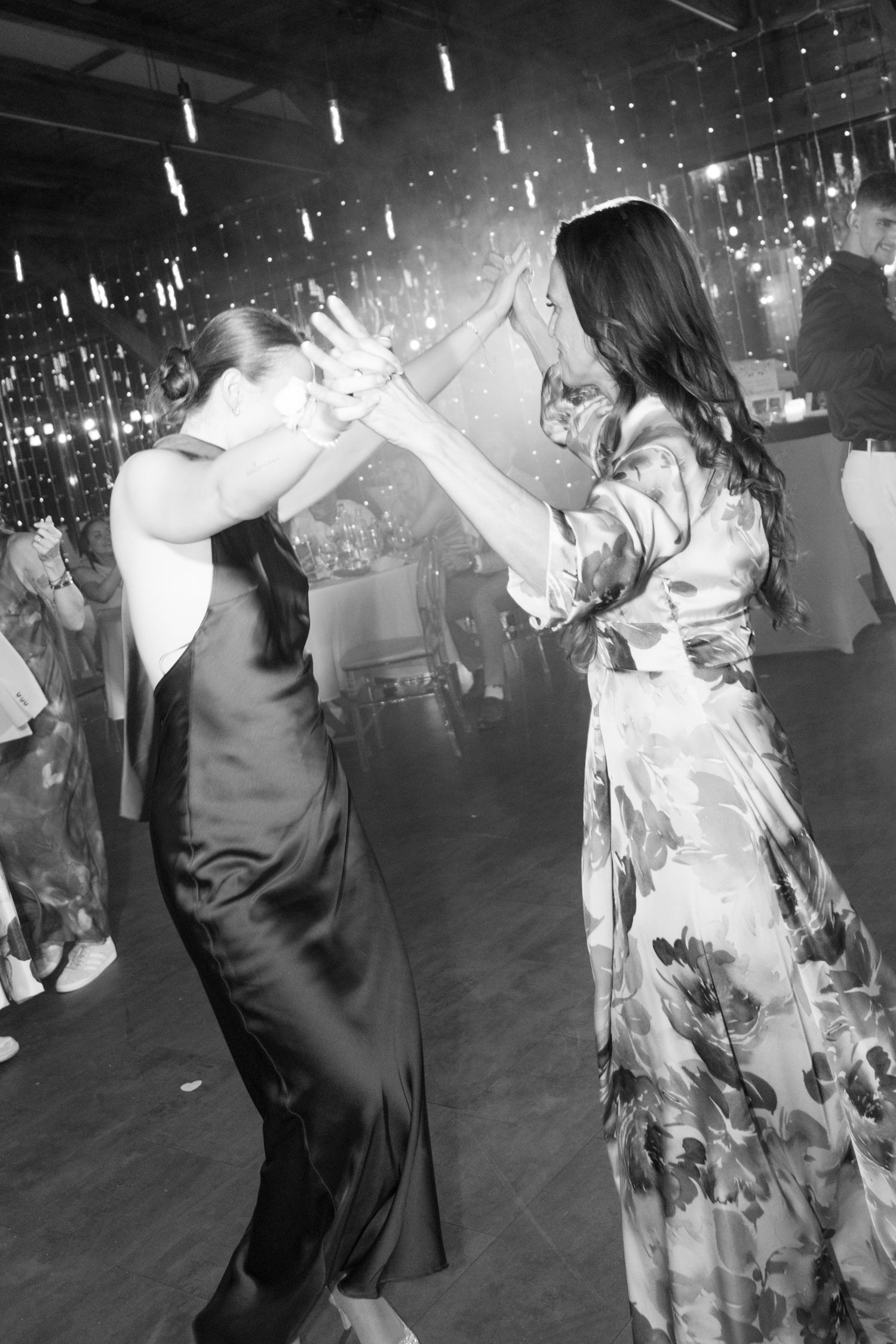 Black and white image of two women dancing together on a glittering wedding reception dance floor. Mallorca wedding photographer and film