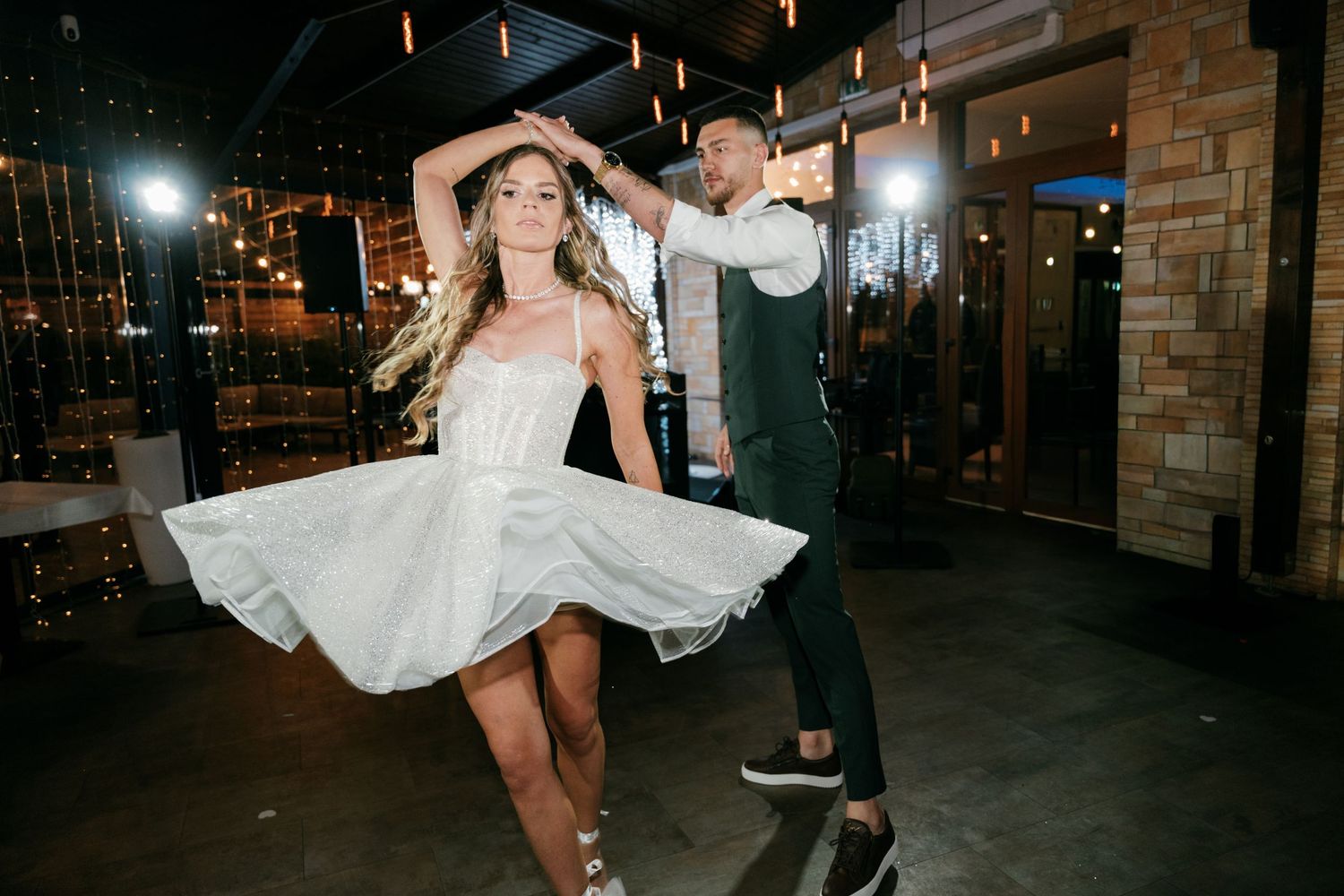 Bride in short white dress being spun by groom on a decorated dance floor at wedding reception. Mallorca wedding photographer and filmmaker.