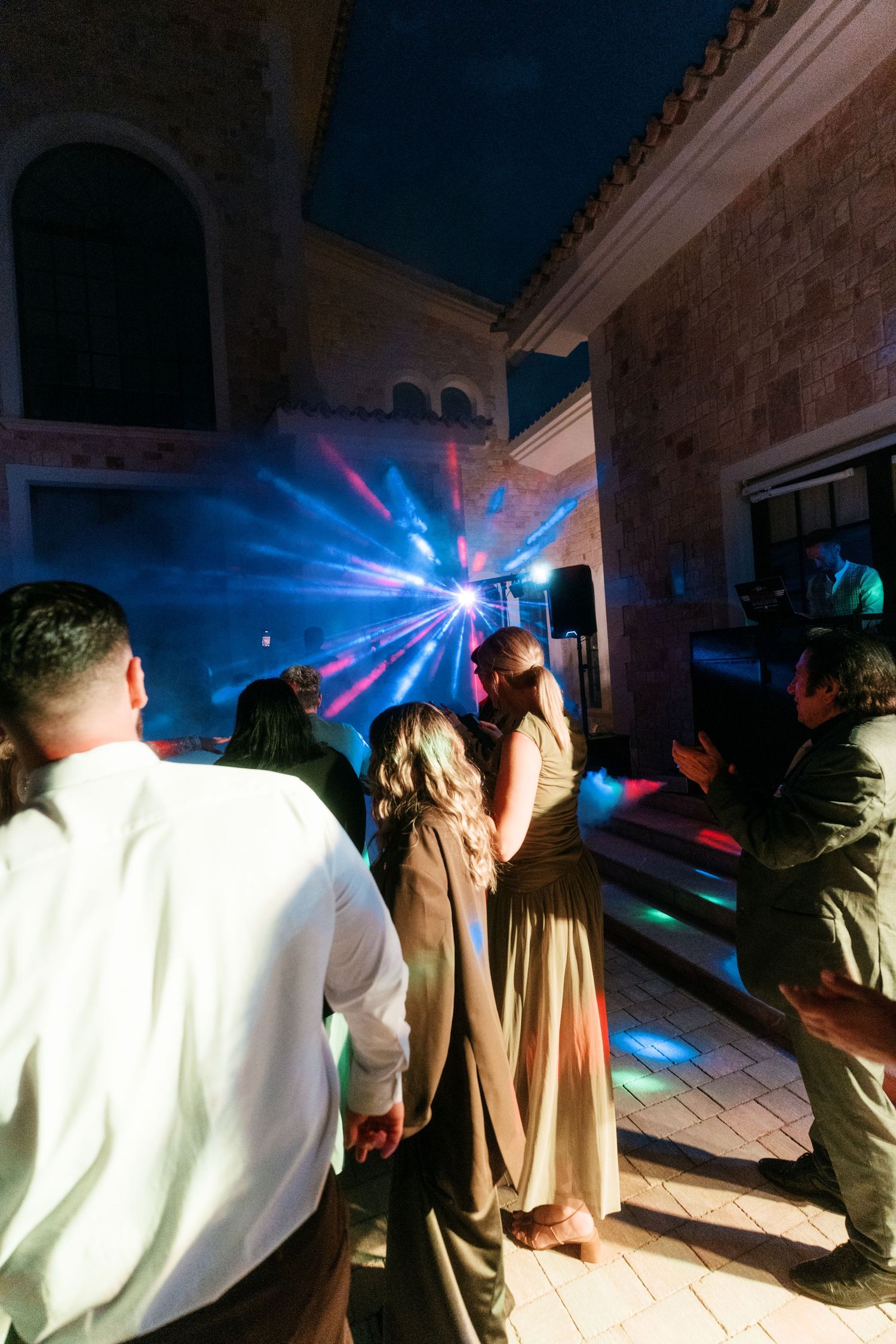 Guests dancing under colorful disco lights at an outdoor evening wedding reception party in Mallorca.