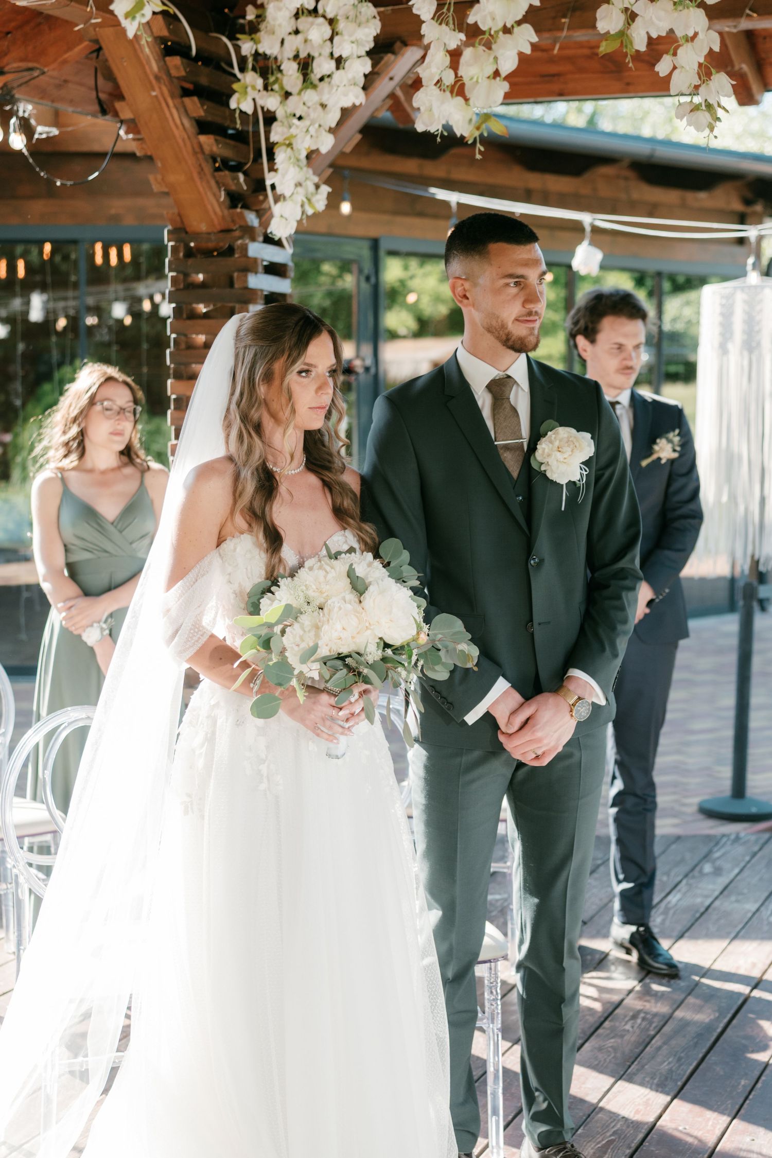 Bride and groom standing at outdoor wedding ceremony altar with white floral arrangements. Mallorca wedding photographer and filmmaker.