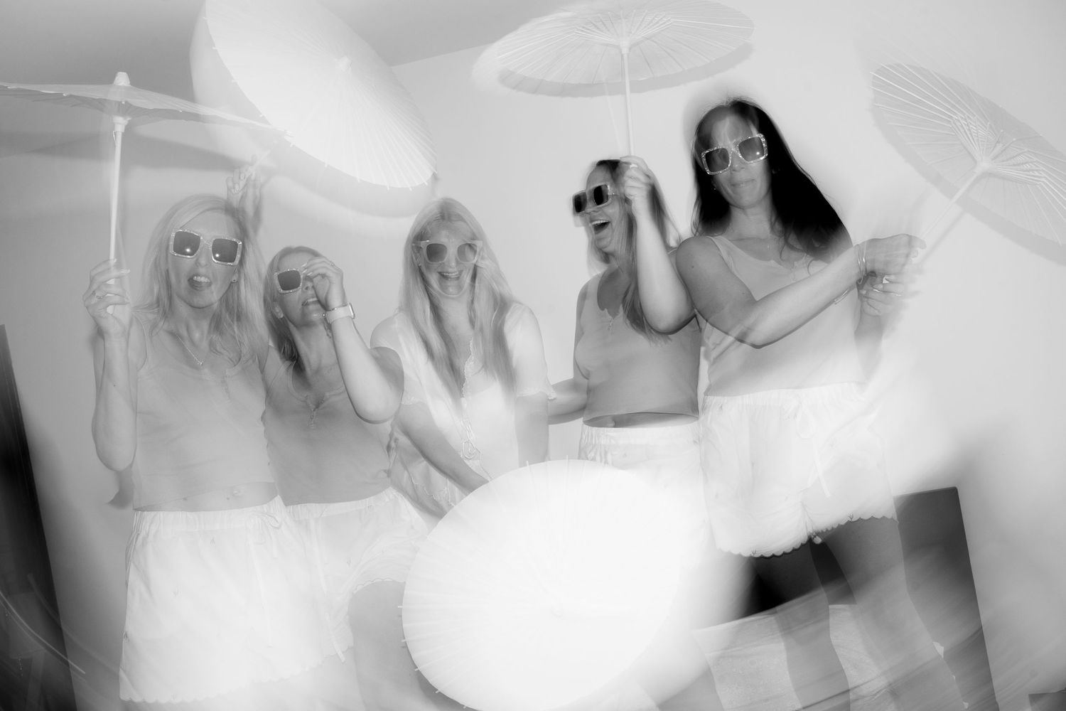 Black and white blurred motion photo of bridesmaids holding parasols indoors. Mallorca wedding photographer, filmmaker