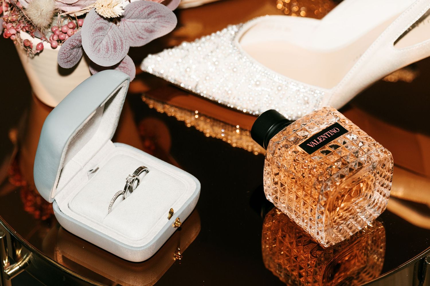 Wedding flat lay featuring a diamond ring in a white box, bridal heels, and Valentino perfume. Italy wedding photographer and filmmaker
