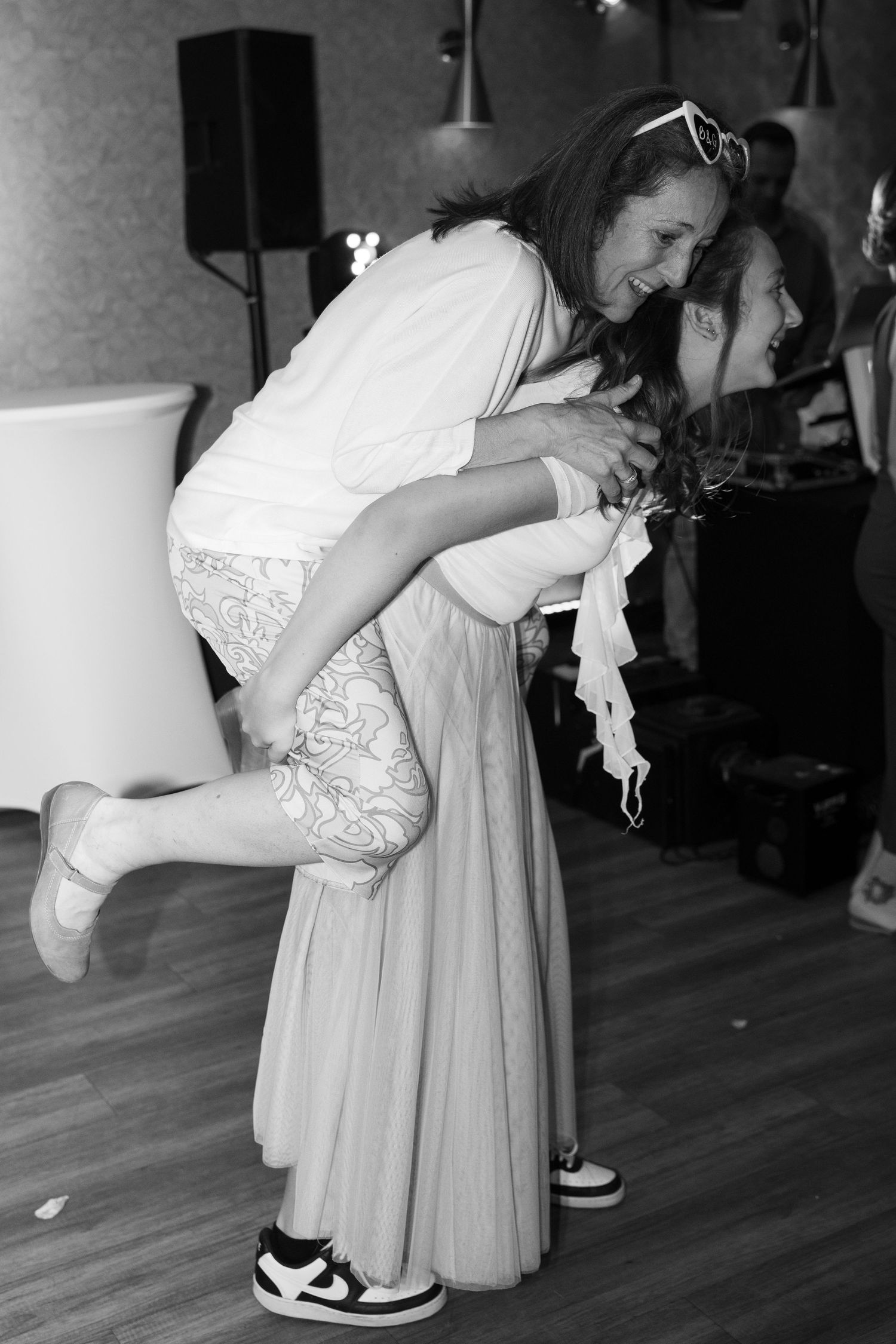 Woman carrying another person on her back laughing at wedding party. Italy wedding photographer and filmmaker