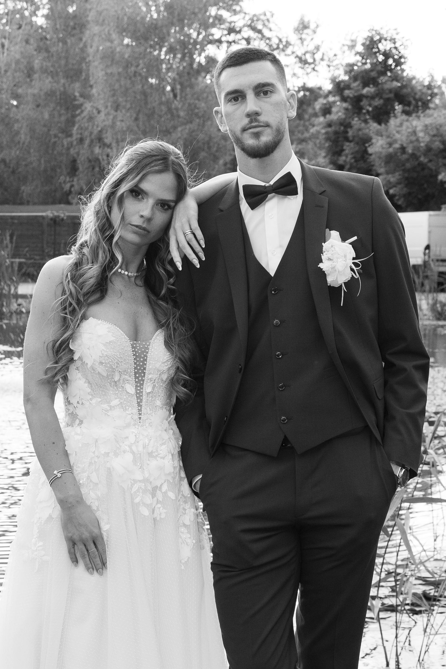 Black and white portrait of elegant bride and groom posing together near tranquil pond. Mallorca wedding photographer and filmmaker.