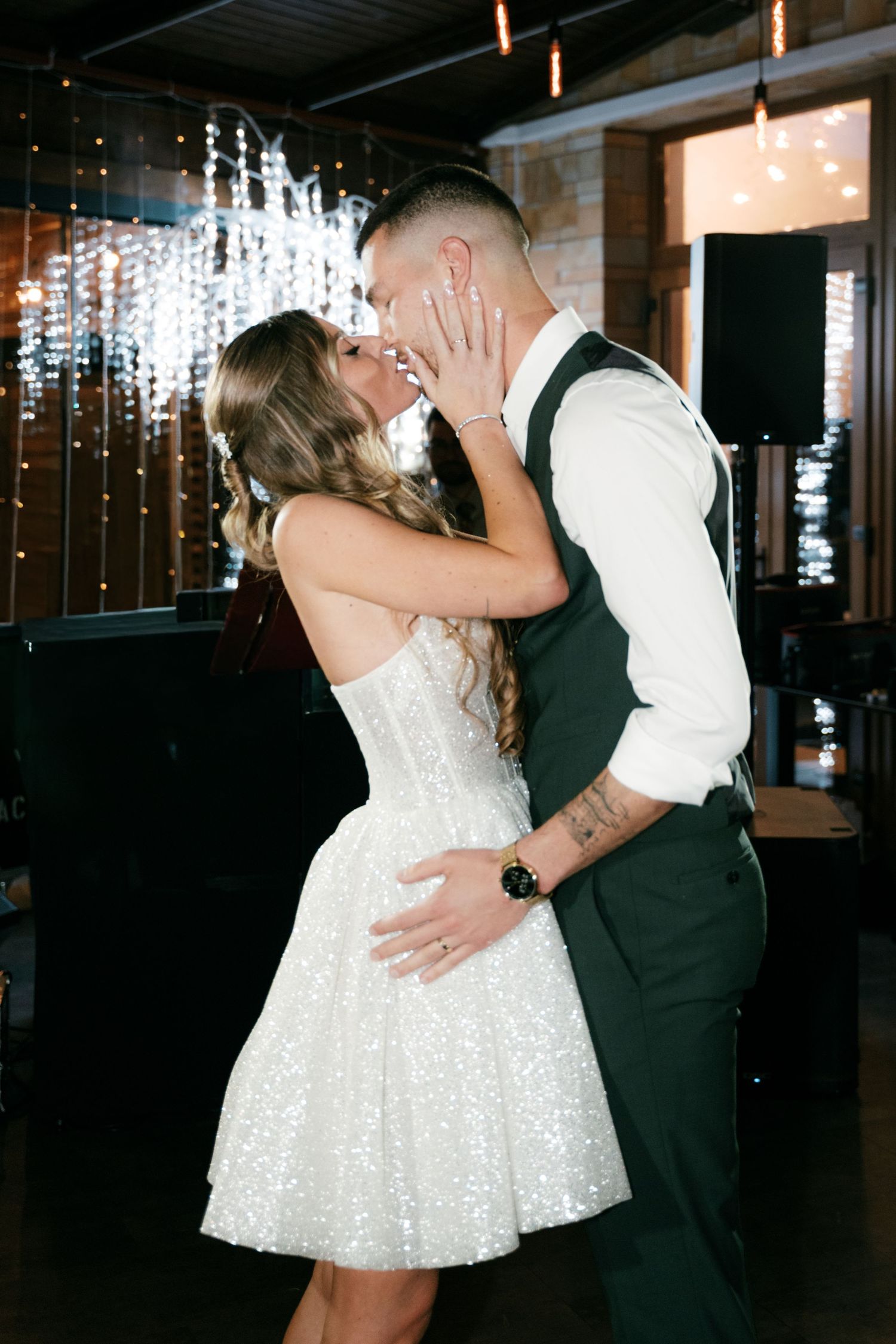 Bride in sequined mini dress and groom in dark vest share a tender kiss on the wedding dance floor. Mallorca wedding photographer and film