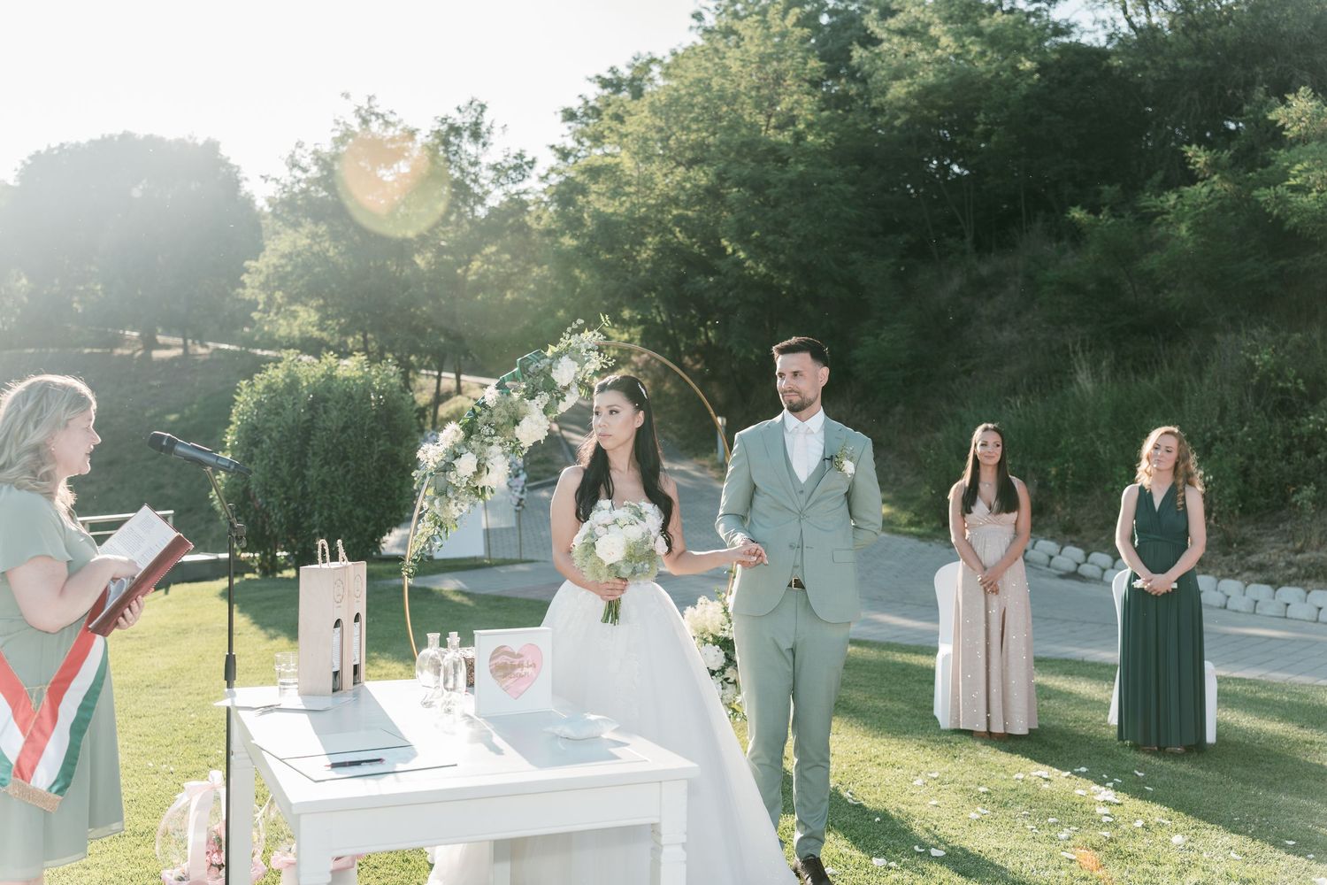 Officiant reads vows as bride and groom stand at sunlit outdoor wedding ceremony altar. Italy wedding photographer and filmmaker