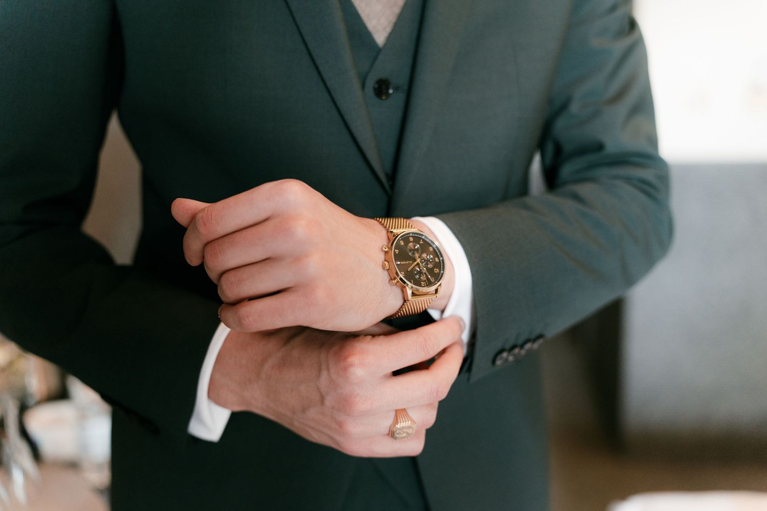 Groom in green suit adjusts gold chronograph watch on wedding day. Mallorca wedding photographer and filmmaker.