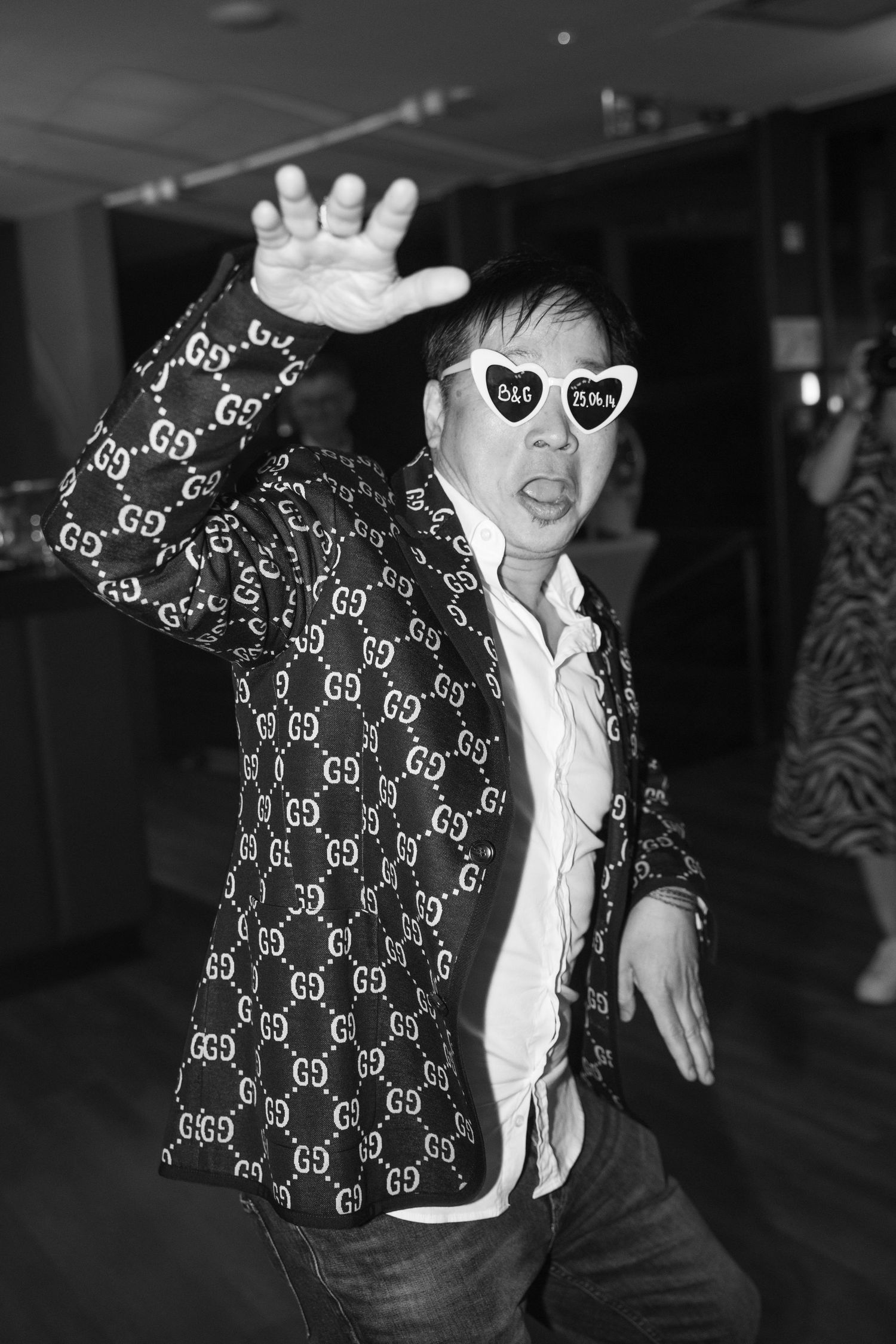 Man in Gucci blazer wearing heart sunglasses dancing in black and white photo. Italy wedding photographer