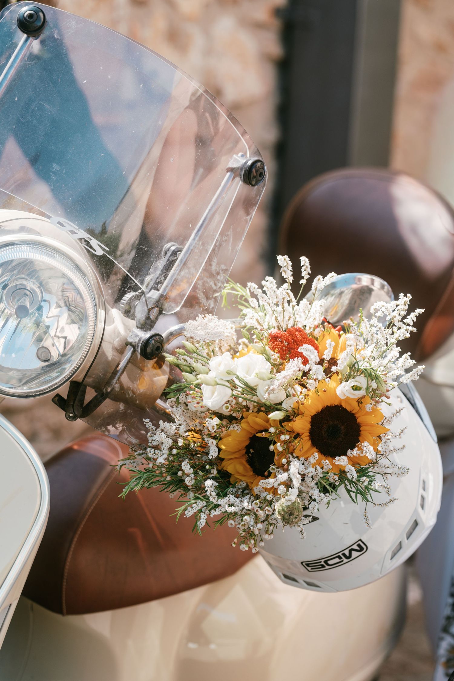 Colorful wedding bouquet with sunflowers in a helmet on a vintage scooter. Tuscany wedding photographer, filmmaker