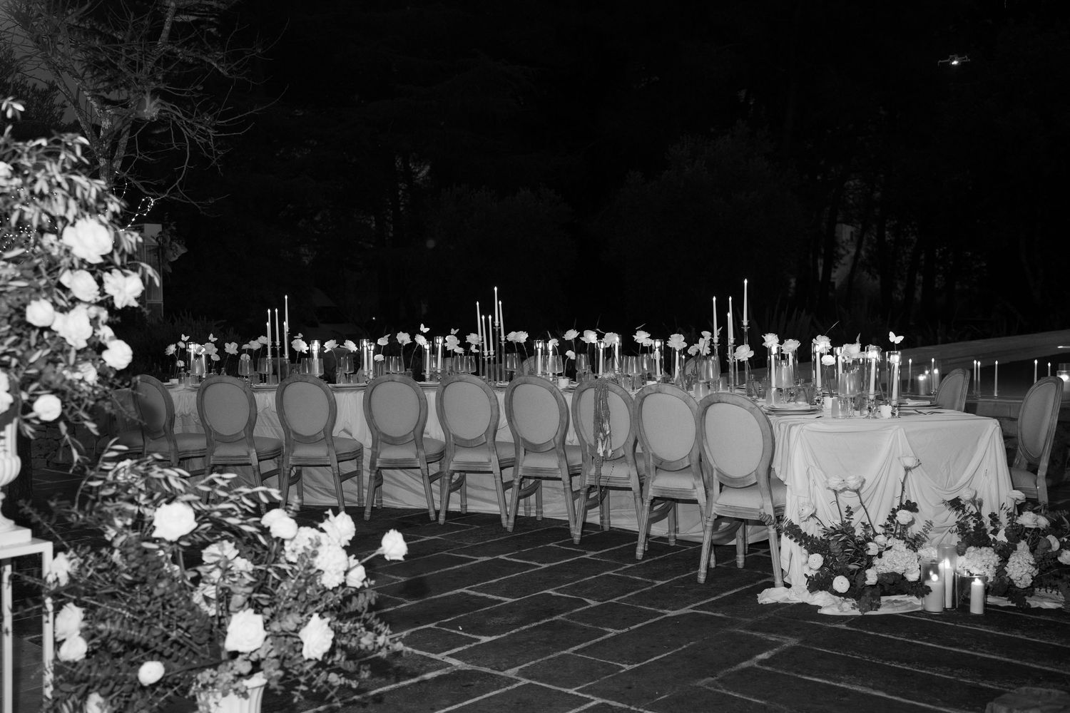 Black and white aerial view of candlelit outdoor wedding reception tables at night. Puglia wedding photographer, film