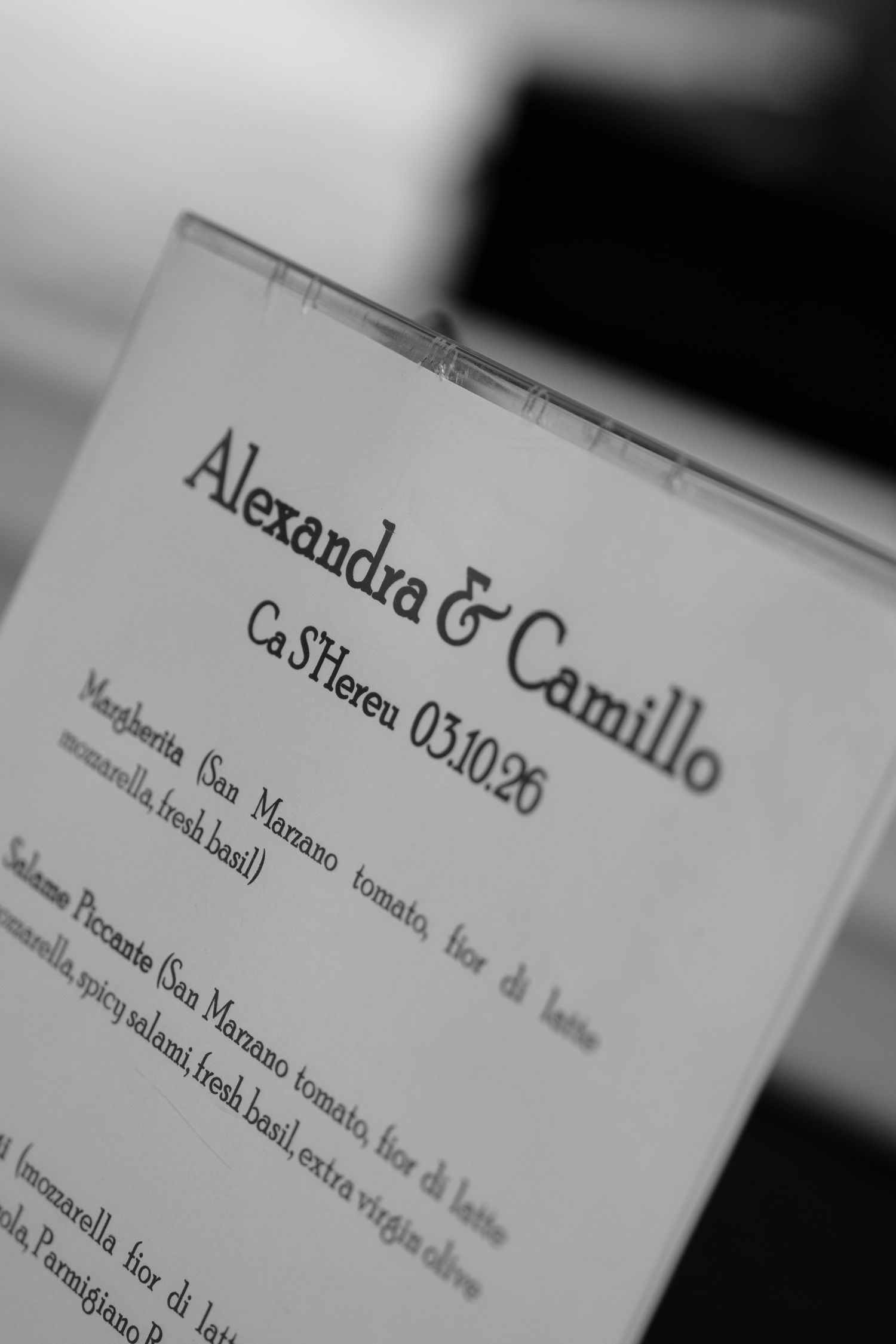 Black and white menu card for Alexandra & Camillo's wedding at Ca S'Hereu listing Italian pizza options.
