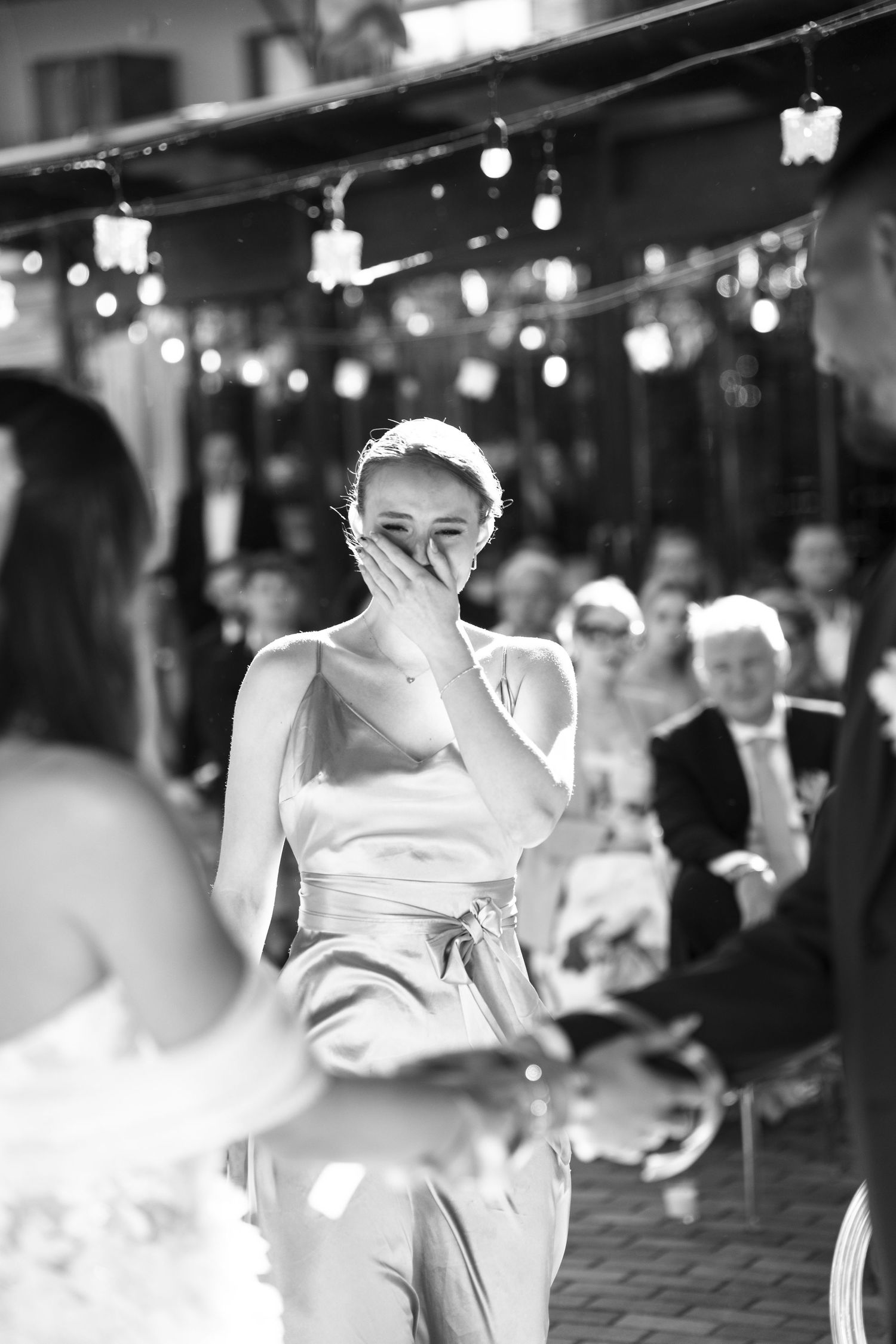 Emotional bridesmaid covering mouth with hand during outdoor wedding reception speech. Mallorca wedding photographer and filmmaker.