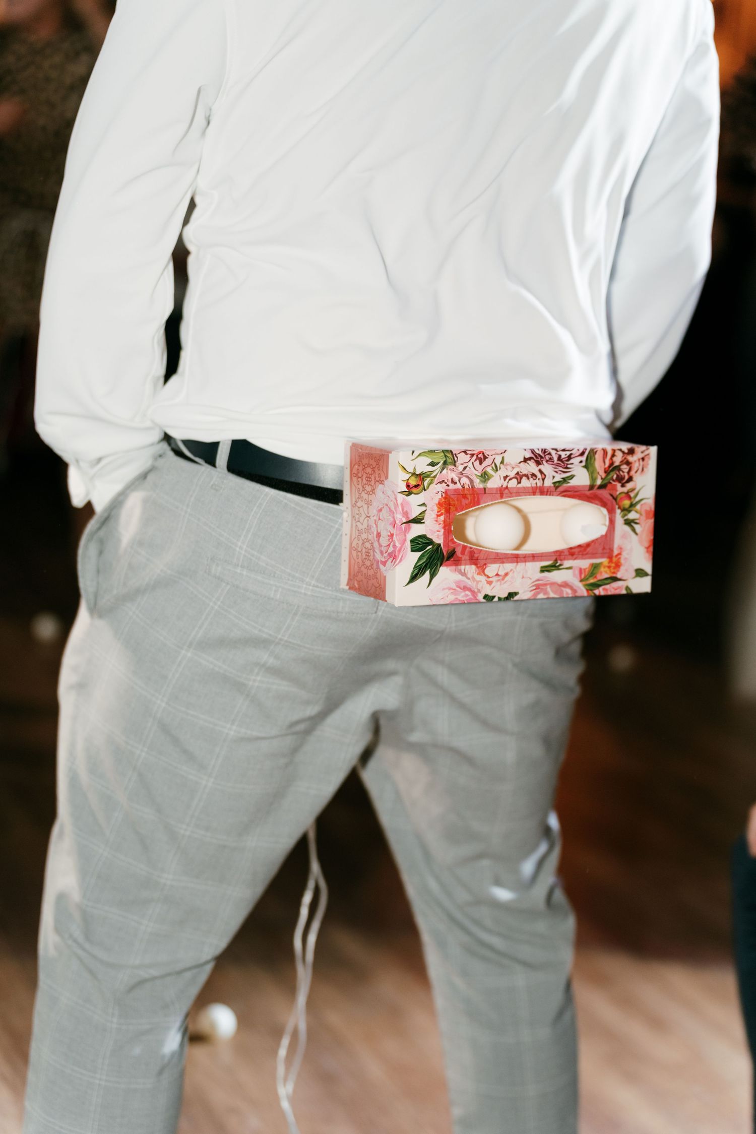 Man in white shirt and gray pants with floral box tucked in belt. Italy wedding photographer and filmmaker