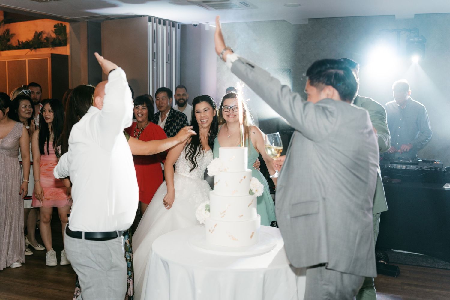 Wedding guests celebrating around the bride and groom near their white tiered cake. Italy wedding photographer and filmmaker