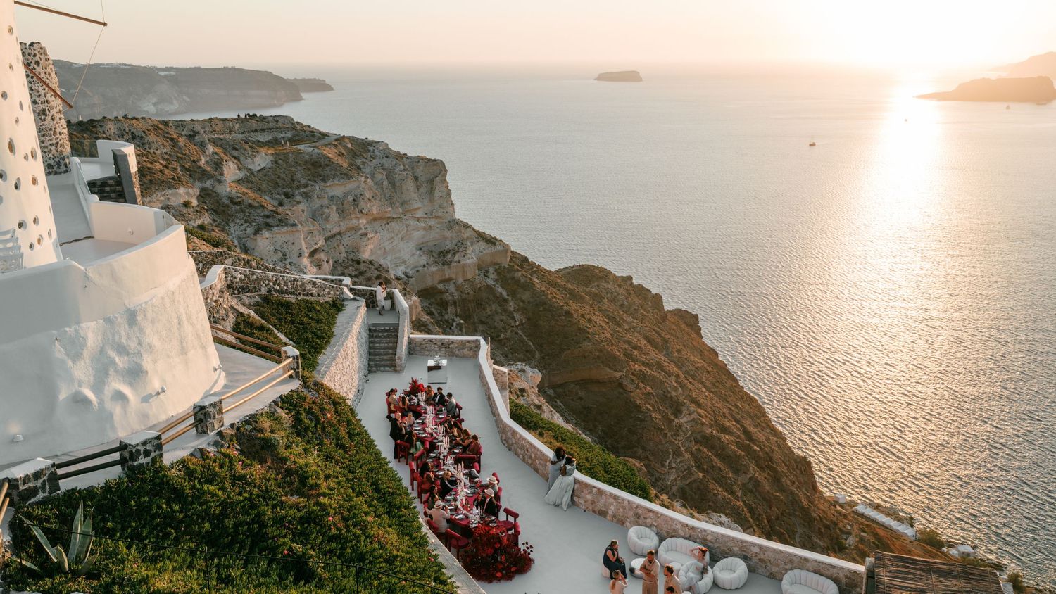 Stunning cliffside restaurant in Santorini with guests dining at sunset overlooking the caldera and Aegean Sea.