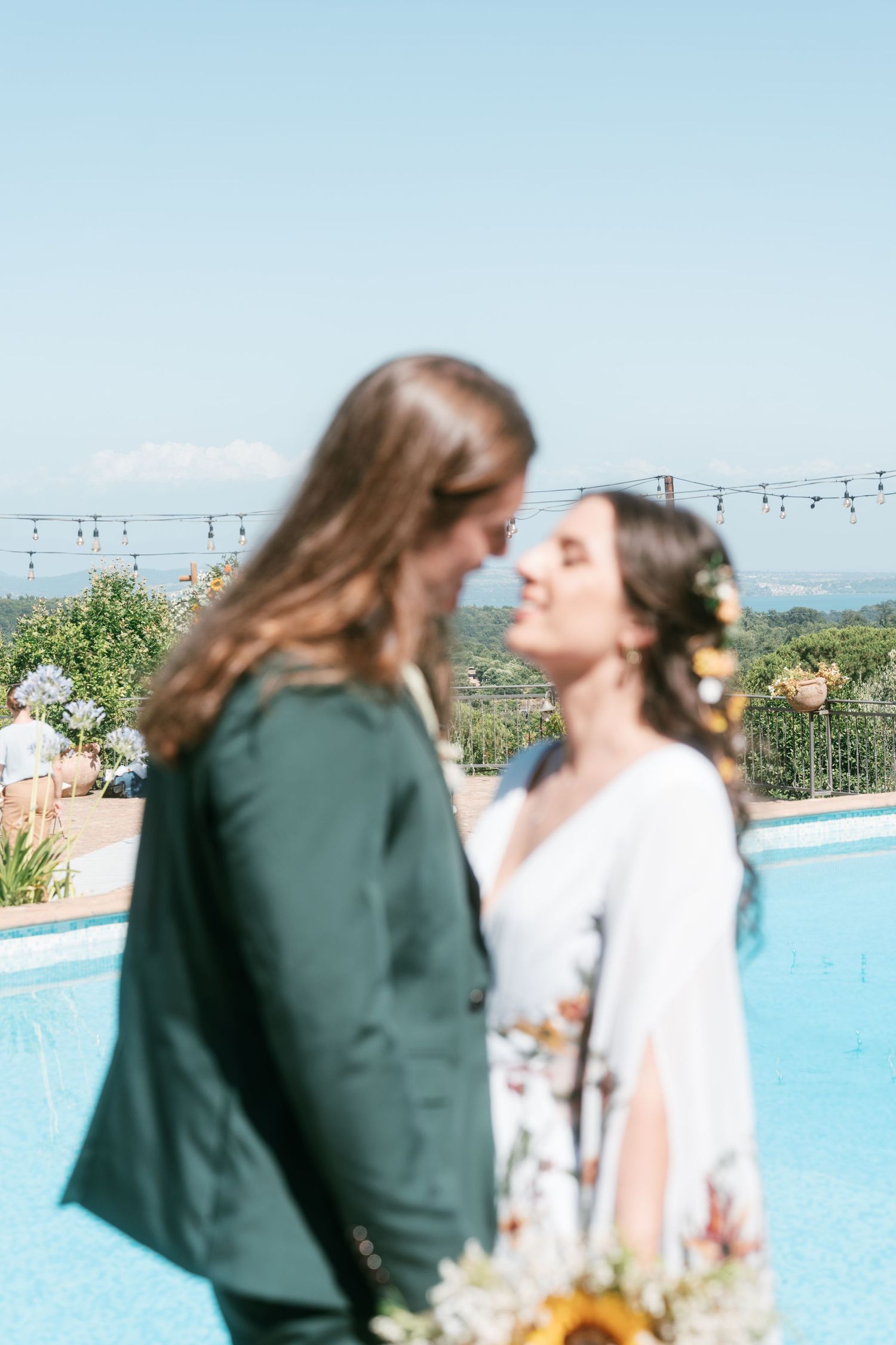 Bride and groom nearly kissing near a pool with scenic landscape in background. Tuscany wedding photographer, filmmaker