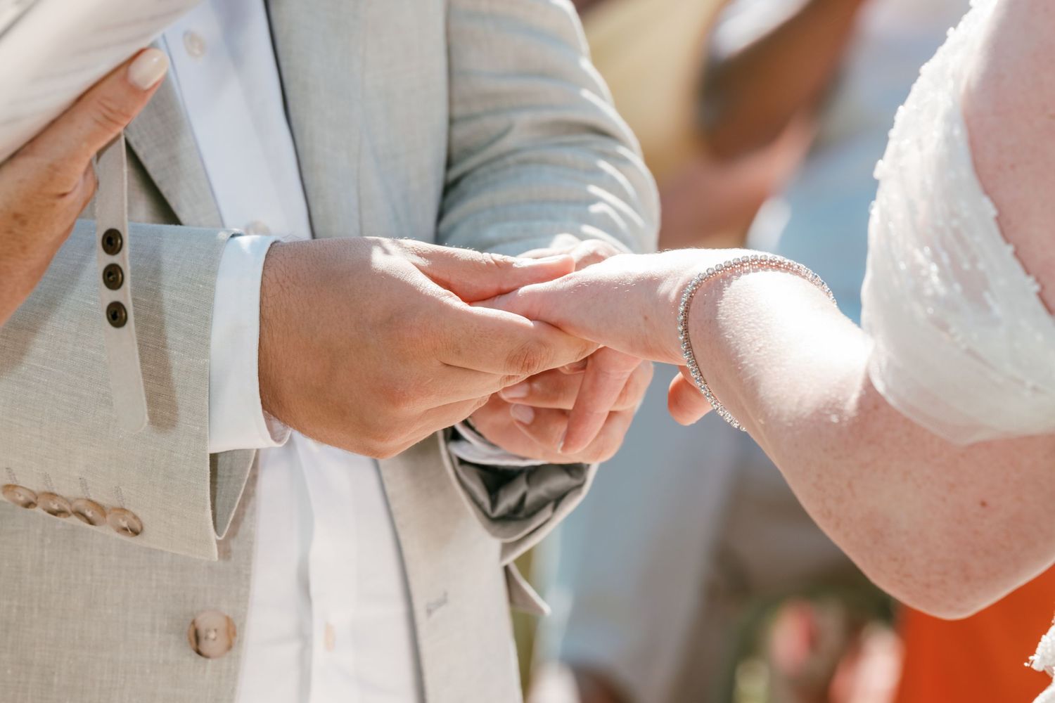 Groom in light gray suit placing wedding ring on bride's finger during outdoor ceremony. Mallorca wedding photographer