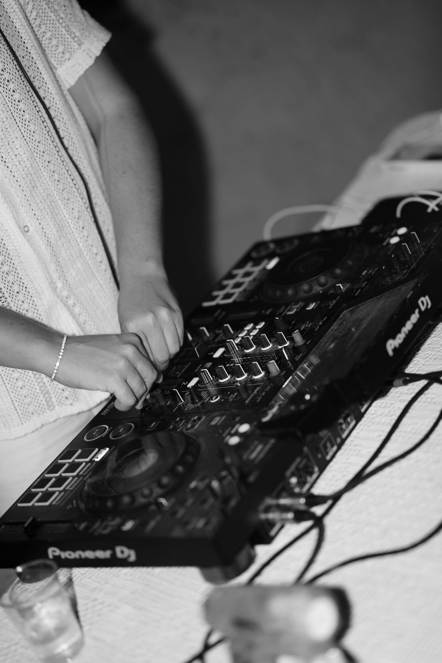 DJ mixing music on a Pioneer DJ controller at a wedding reception in black and white photography.