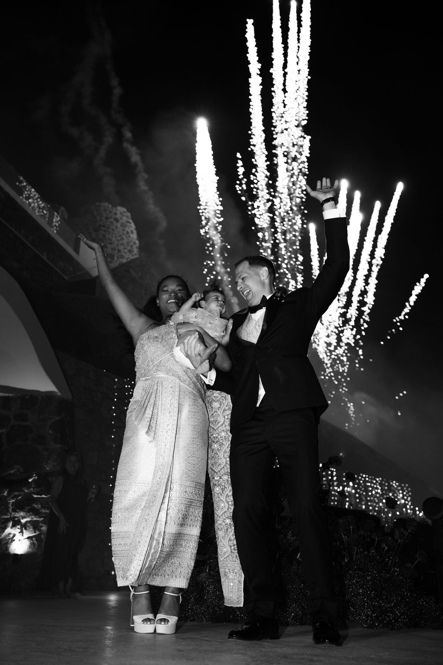 Black and white photo of a joyful couple celebrating with fireworks at their wedding reception.