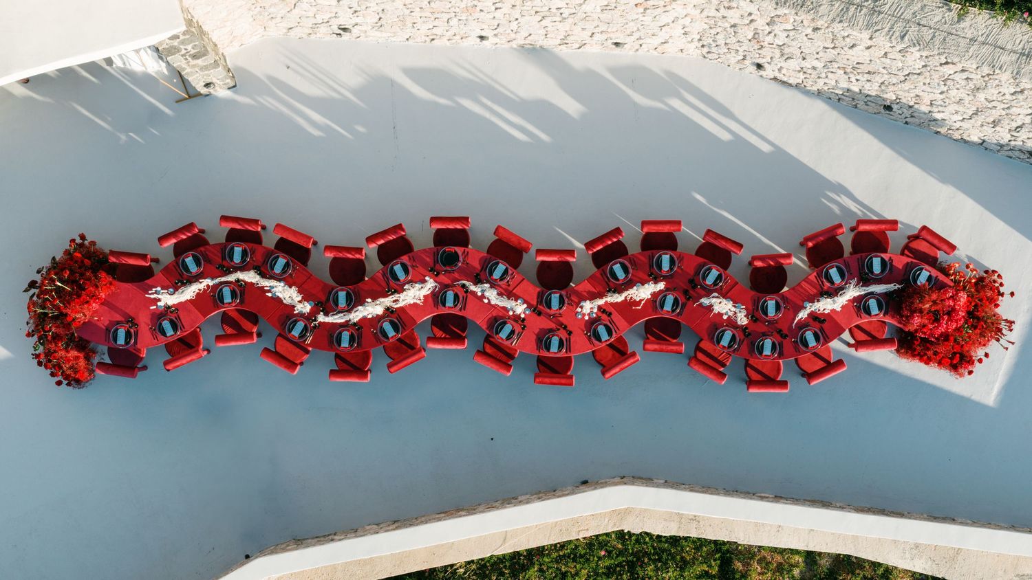Aerial view of a large group dressed in red forming a decorative pattern on a light-colored surface.