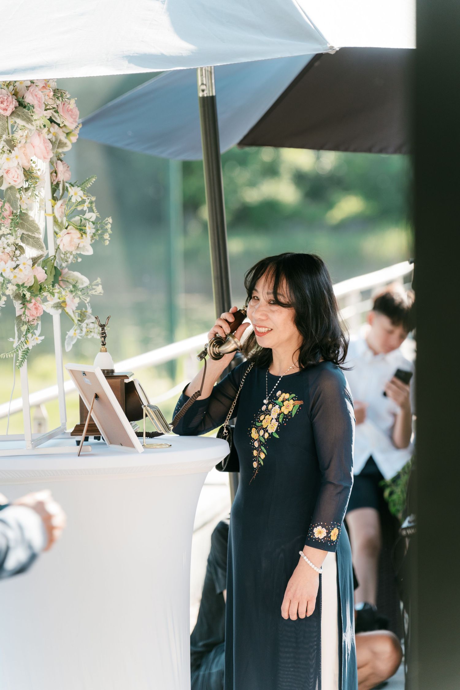 Wedding officiant speaking into microphone at outdoor ceremony beneath white canopy. Italy wedding photographer and filmmaker