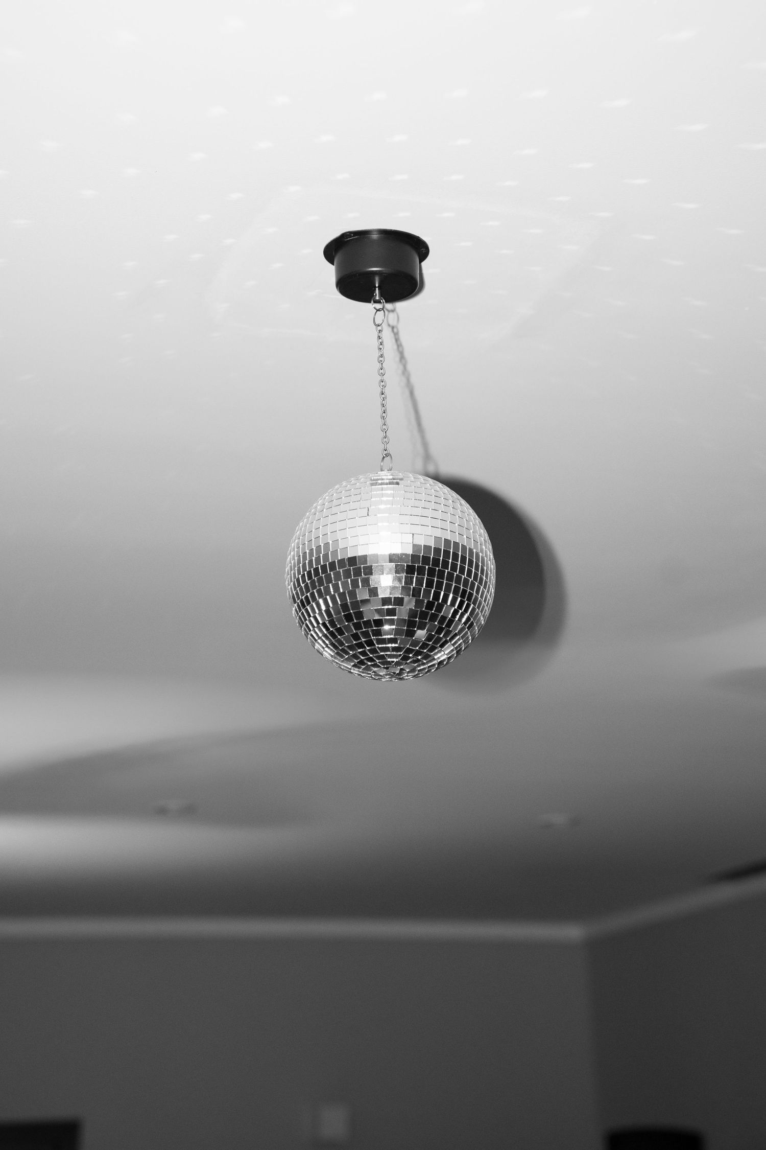 Vintage mirror disco ball hanging from ceiling captured in elegant black and white photography. Tuscany wedding photographer, filmmaker