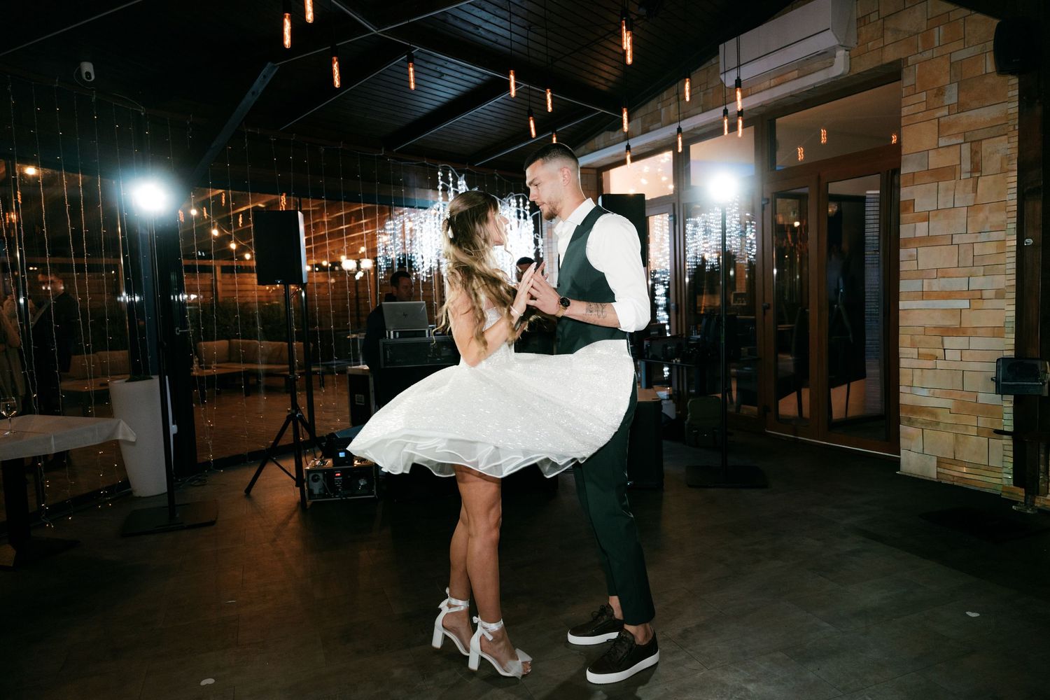Bride and groom sharing their first dance in a warmly lit wedding reception venue. Mallorca wedding photographer and filmmaker.