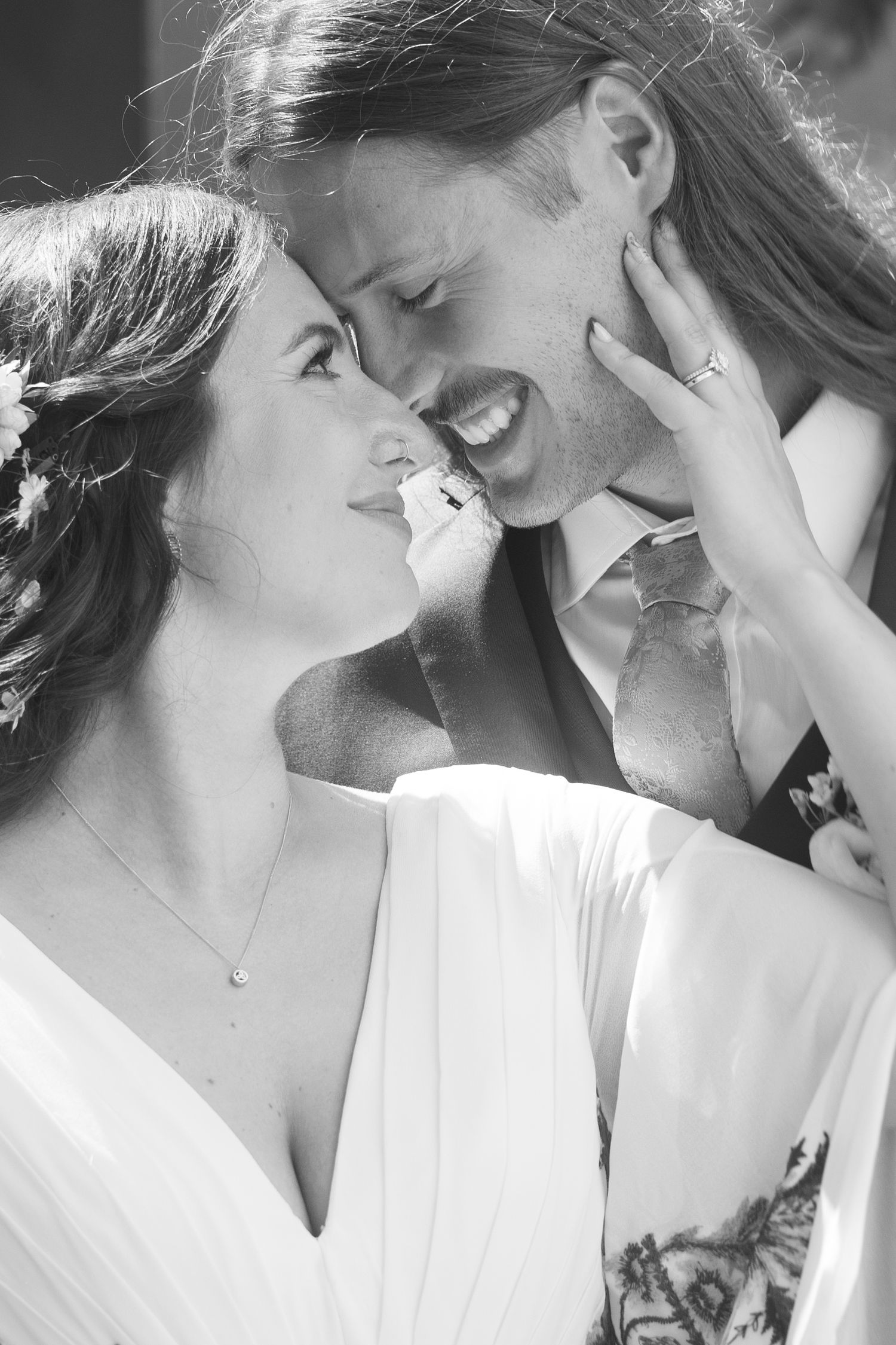 Black and white photo of smiling bride and groom touching foreheads on wedding day. Tuscany wedding photographer, filmmaker