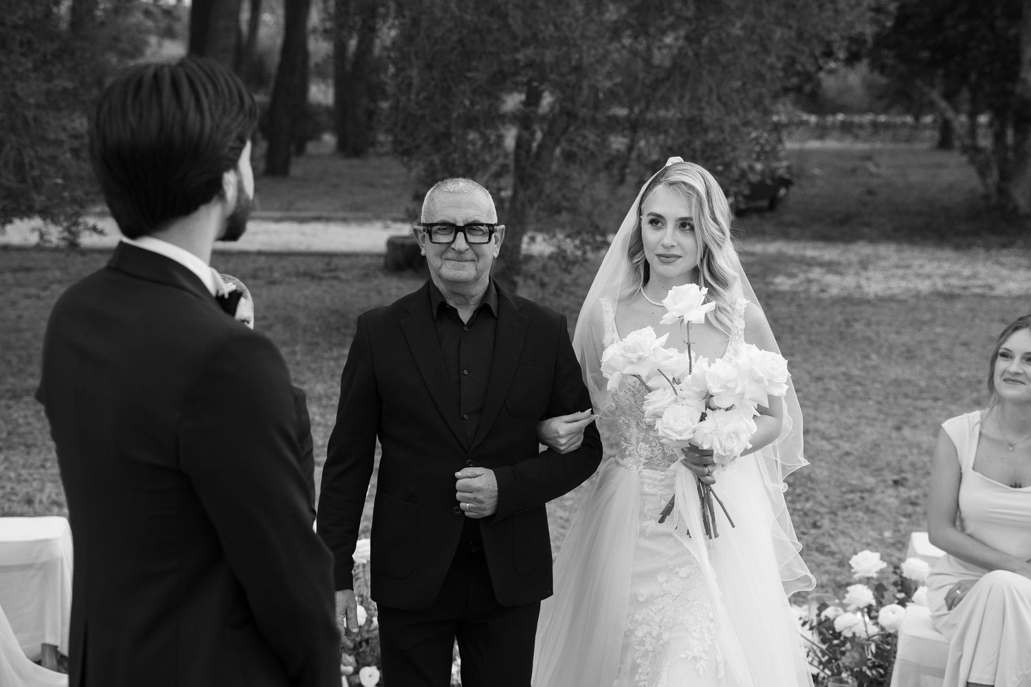 Black and white photo of bride being walked down the aisle by her father at outdoor wedding. Puglia wedding photographer, film